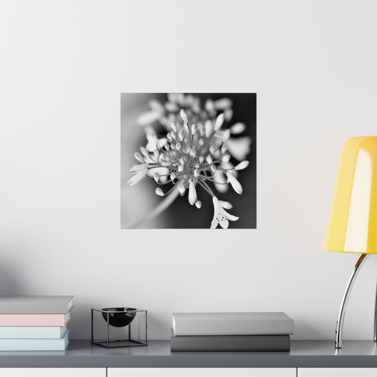 Floral artwork on a wall above a table with books and a lamp.