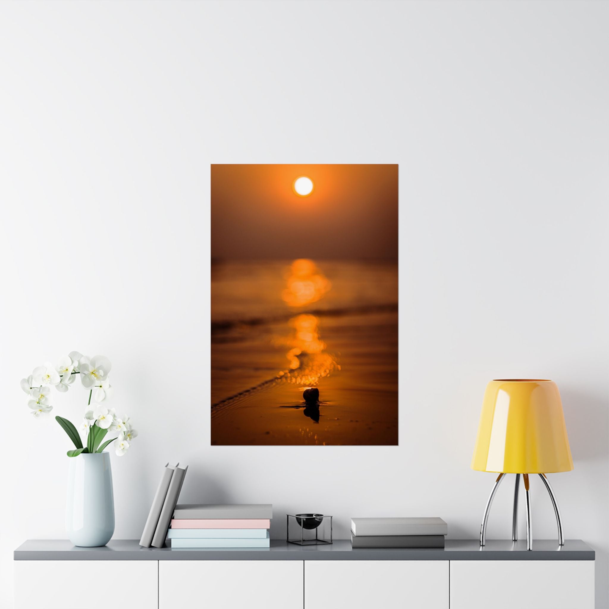 Sunset over water with a small boat on a white wall above a shelf with decor items.