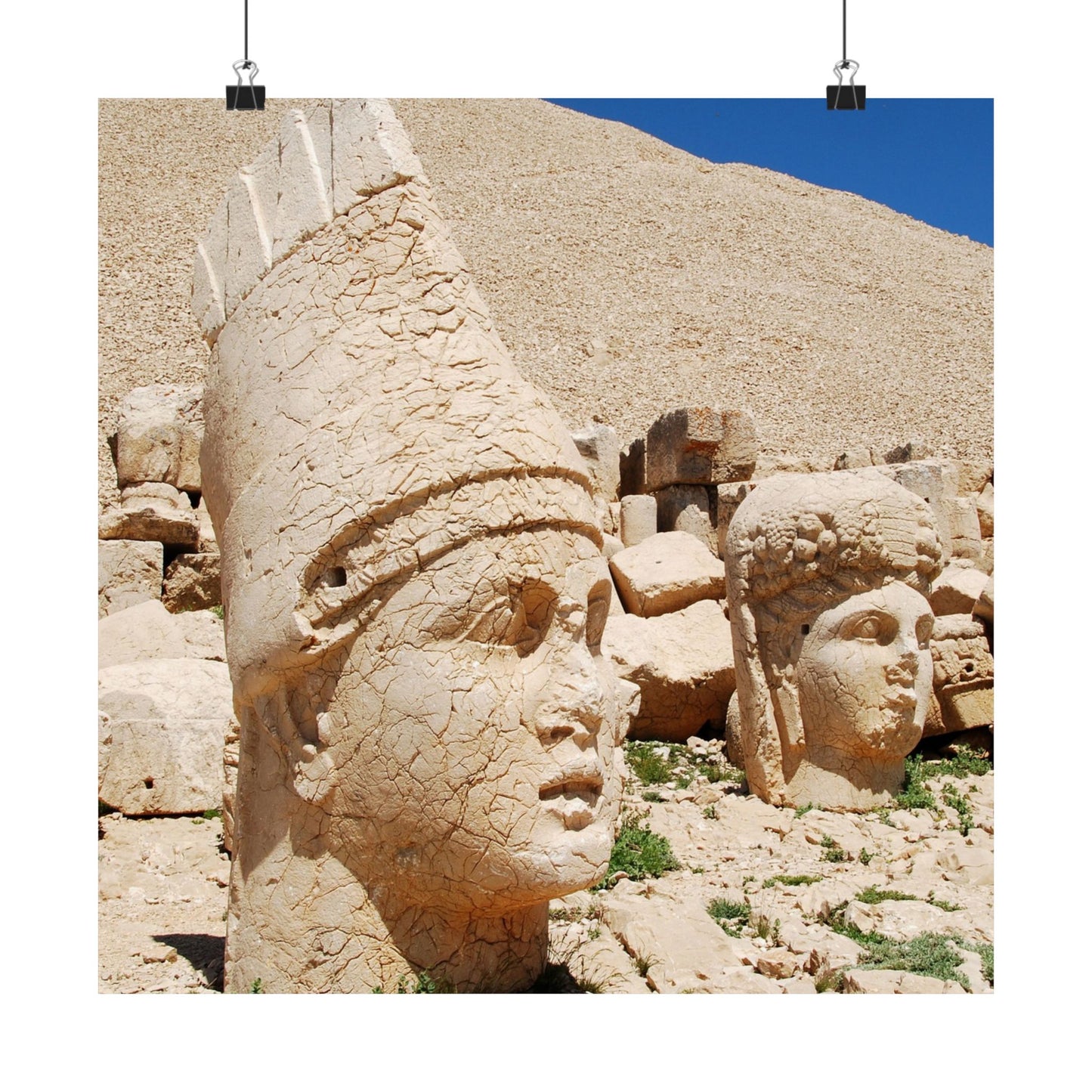 Stone statues with headresses on a rocky hillside under a blue sky