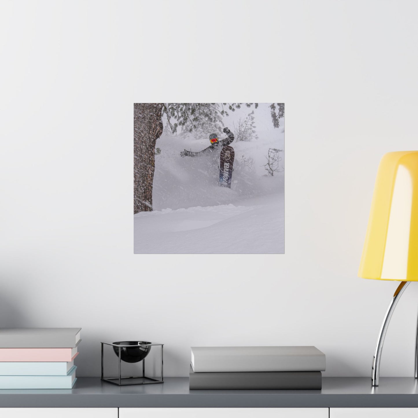 Poster of a person skiing on a snowy landscape above a desk with books and a lamp.