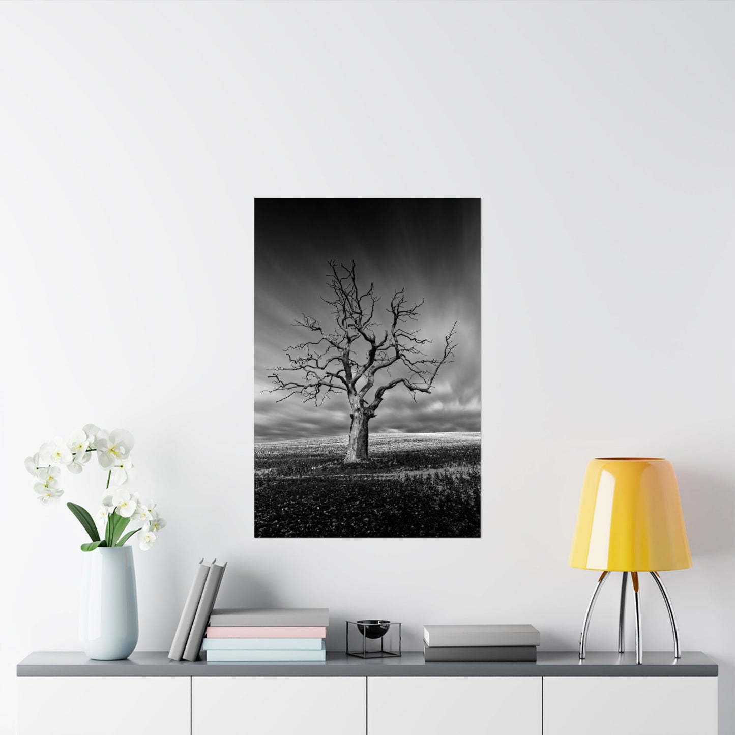 Framed black and white print of a tree on a wall above a shelf with decor items.
