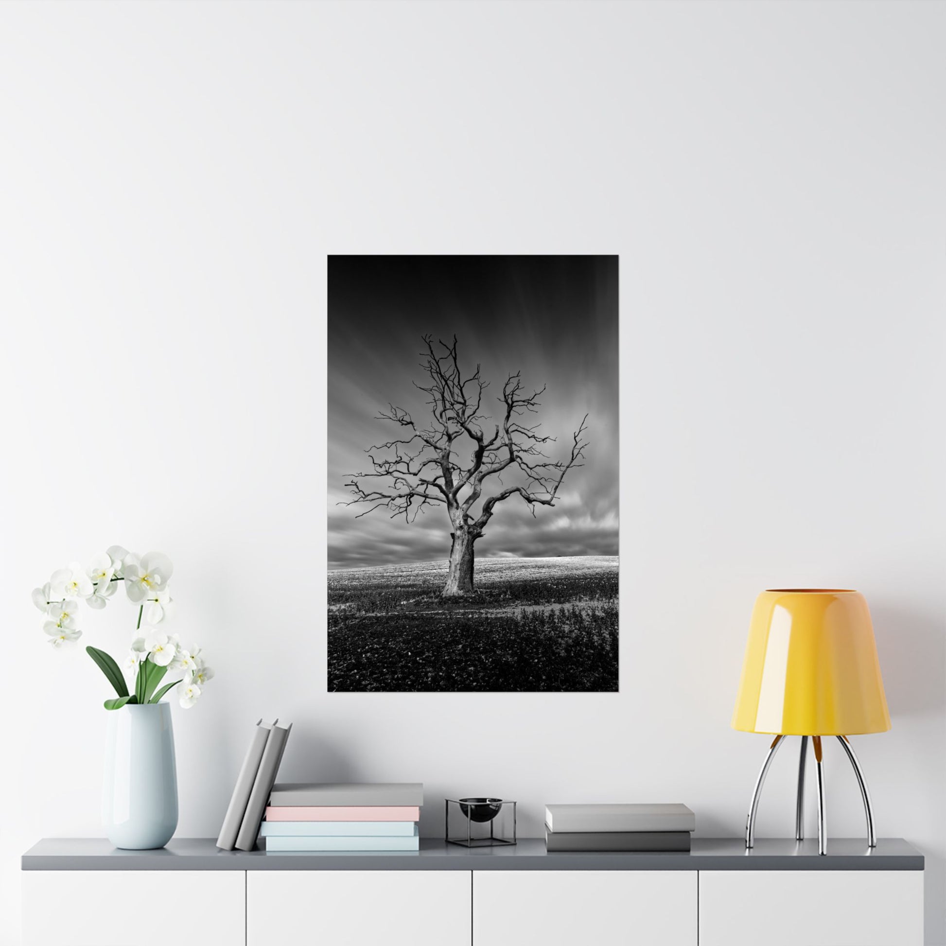 Framed black and white print of a tree on a wall above a shelf with decor items.