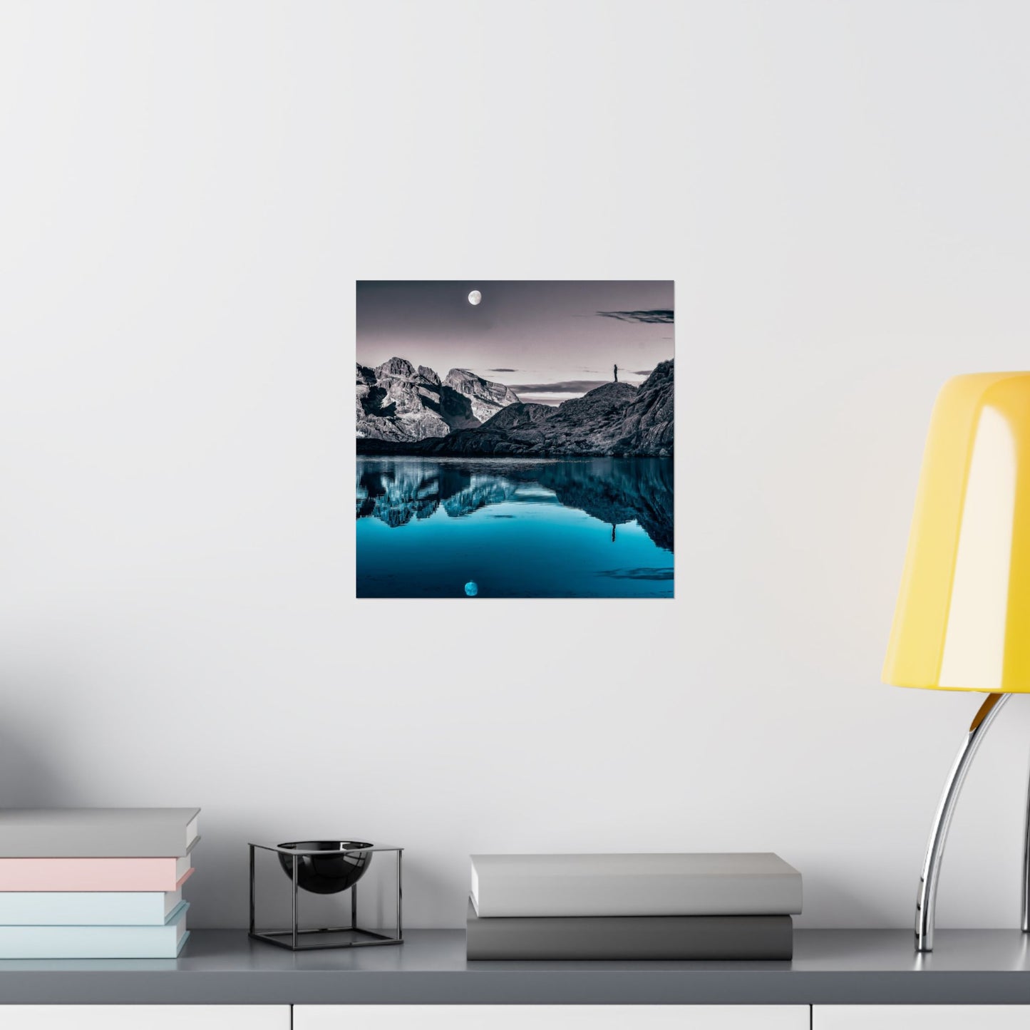 Wall art of a mountain landscape with a lake on a white wall above a desk.