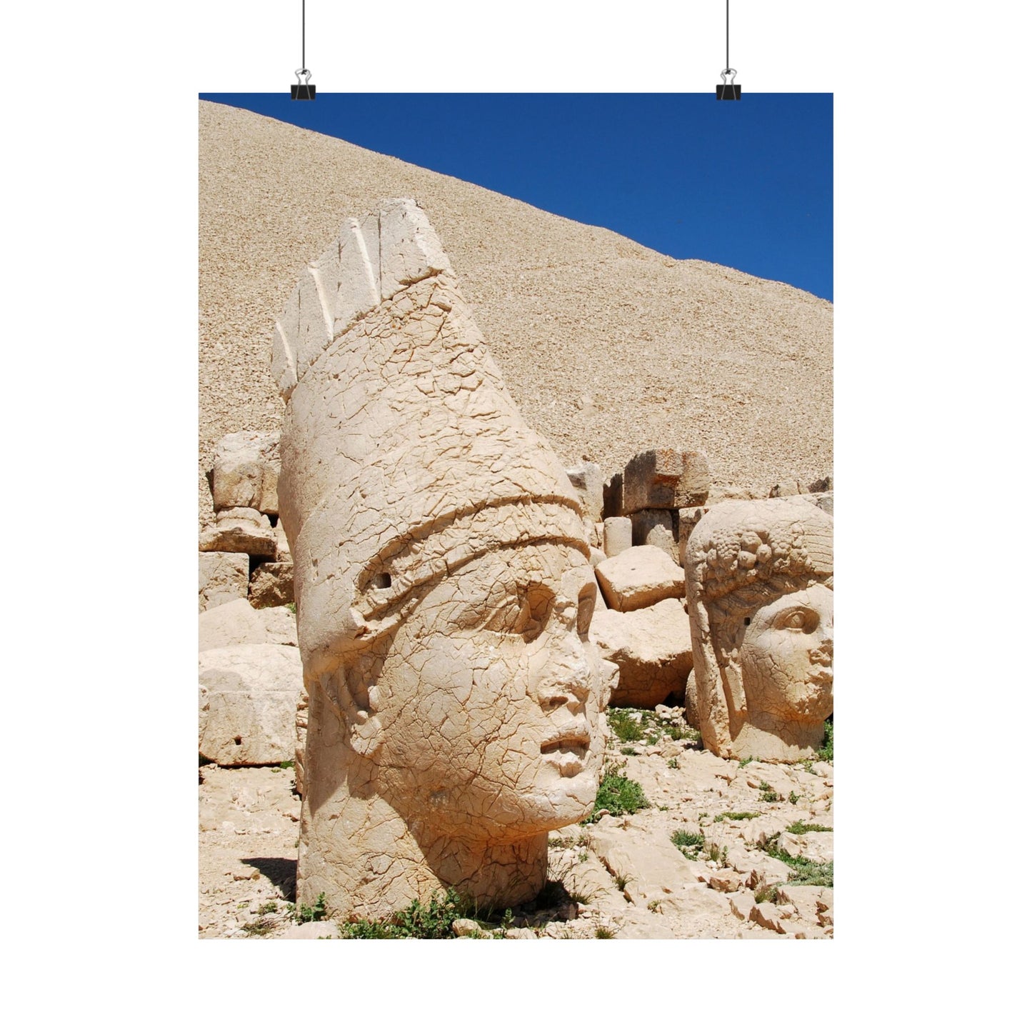 Stone heads of ancient statues on a rocky hillside with blue sky