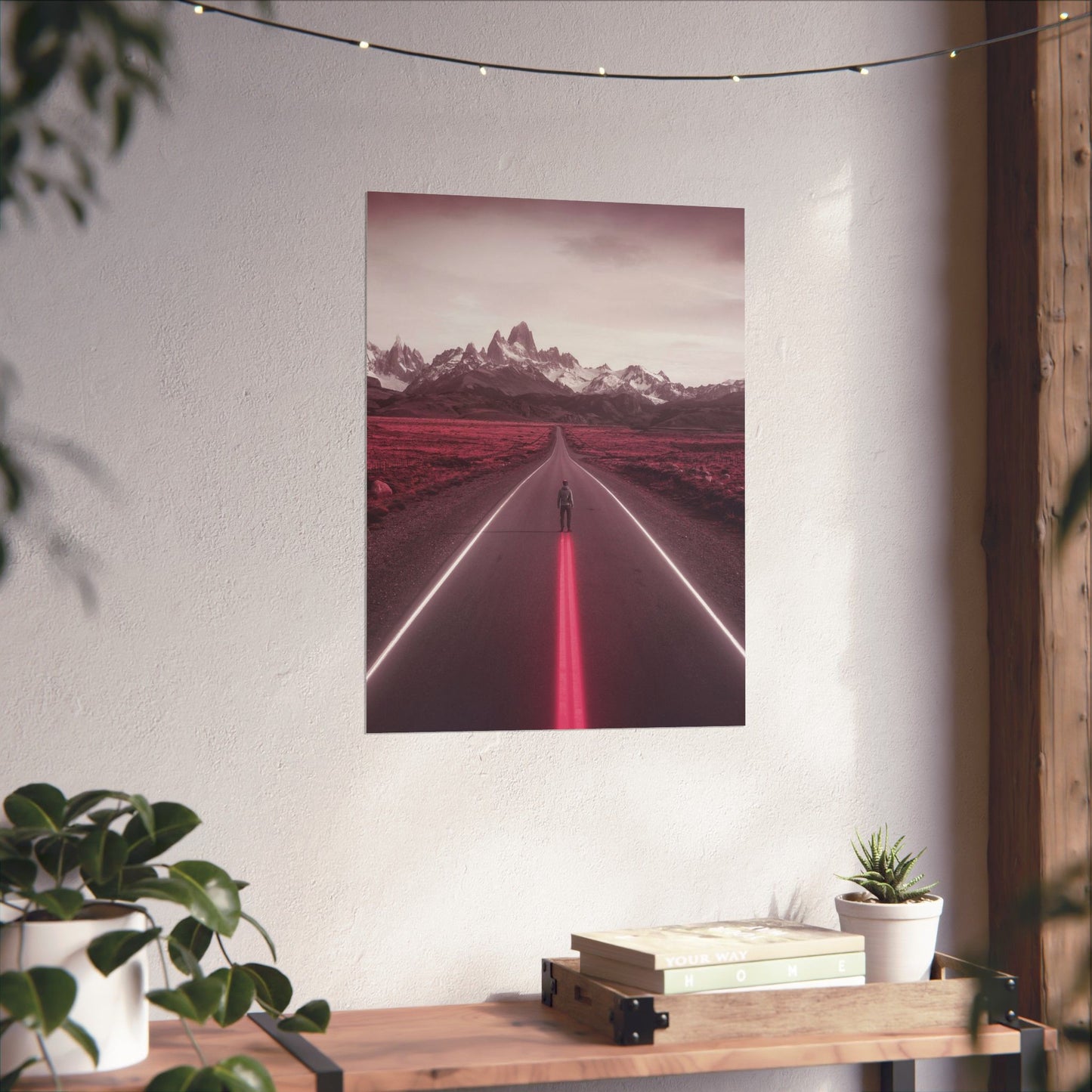 Framed artwork of a road with mountains on a white wall above a wooden shelf.