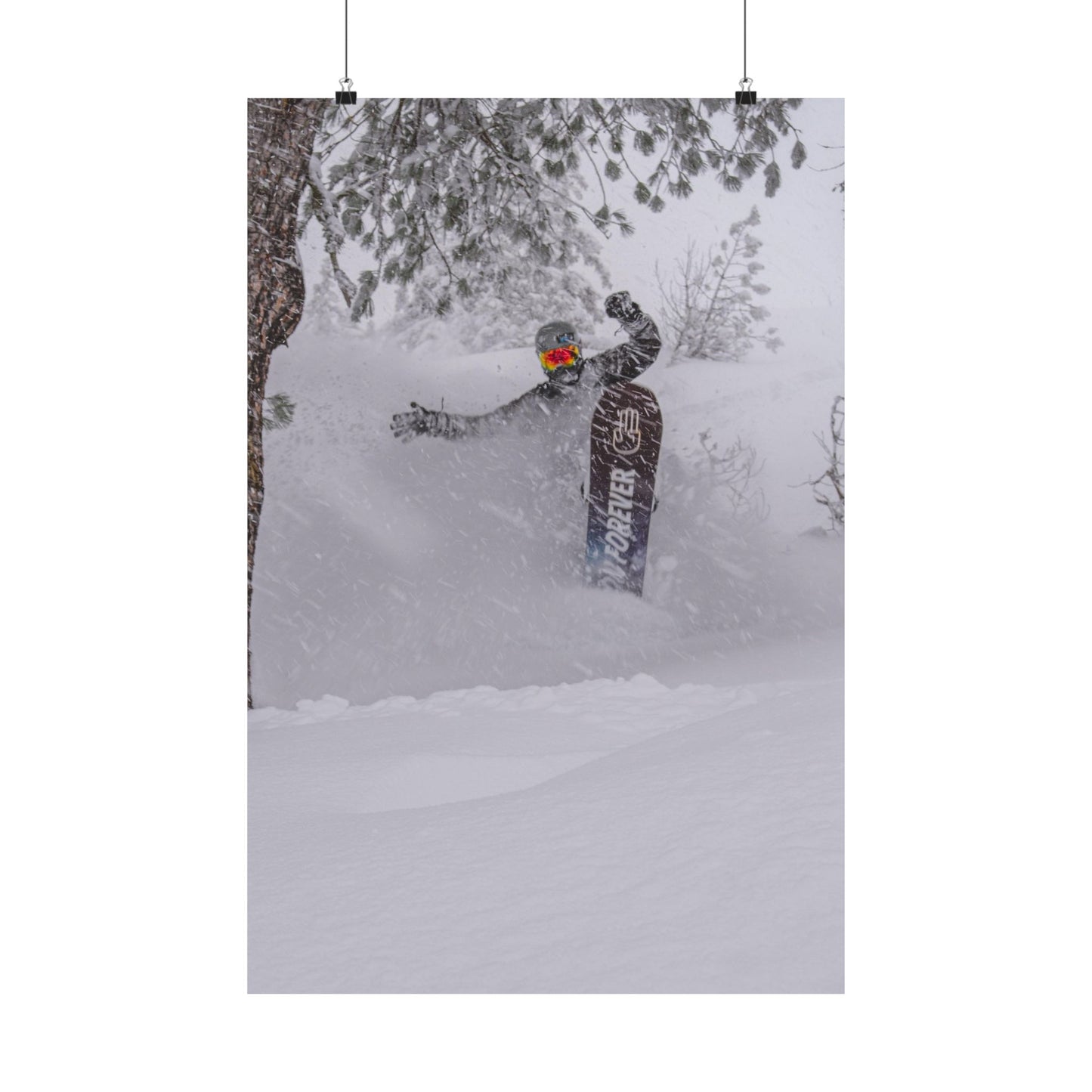 Person snowboarding in a snowy forest with a snowboard featuring the brand 'Burton'.