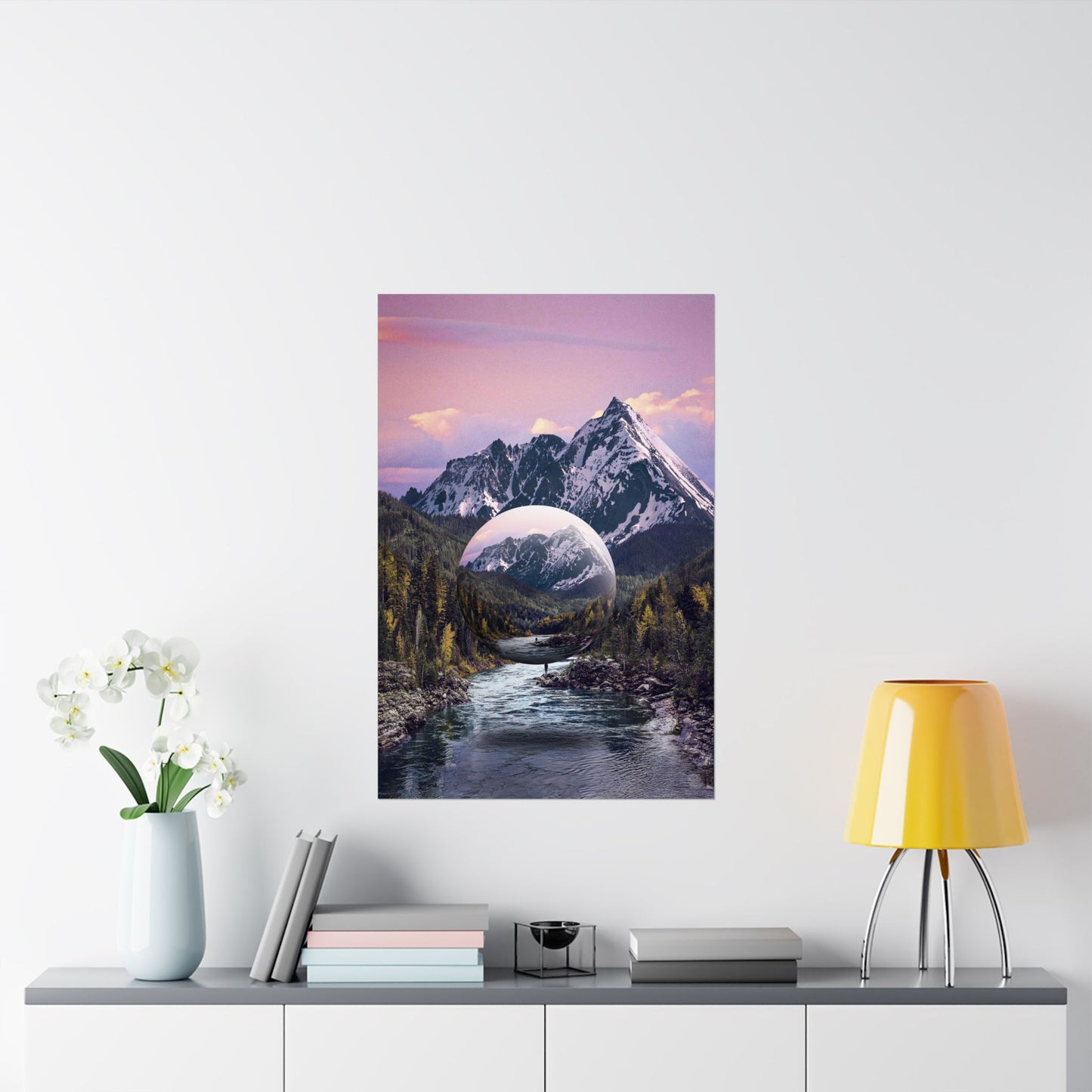 Framed mountain landscape print on a wall above a table with decor items.