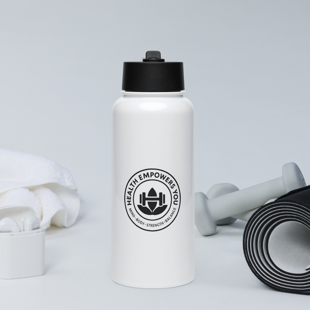 White water bottle with black lid and logo on a light gray background with fitness equipment.