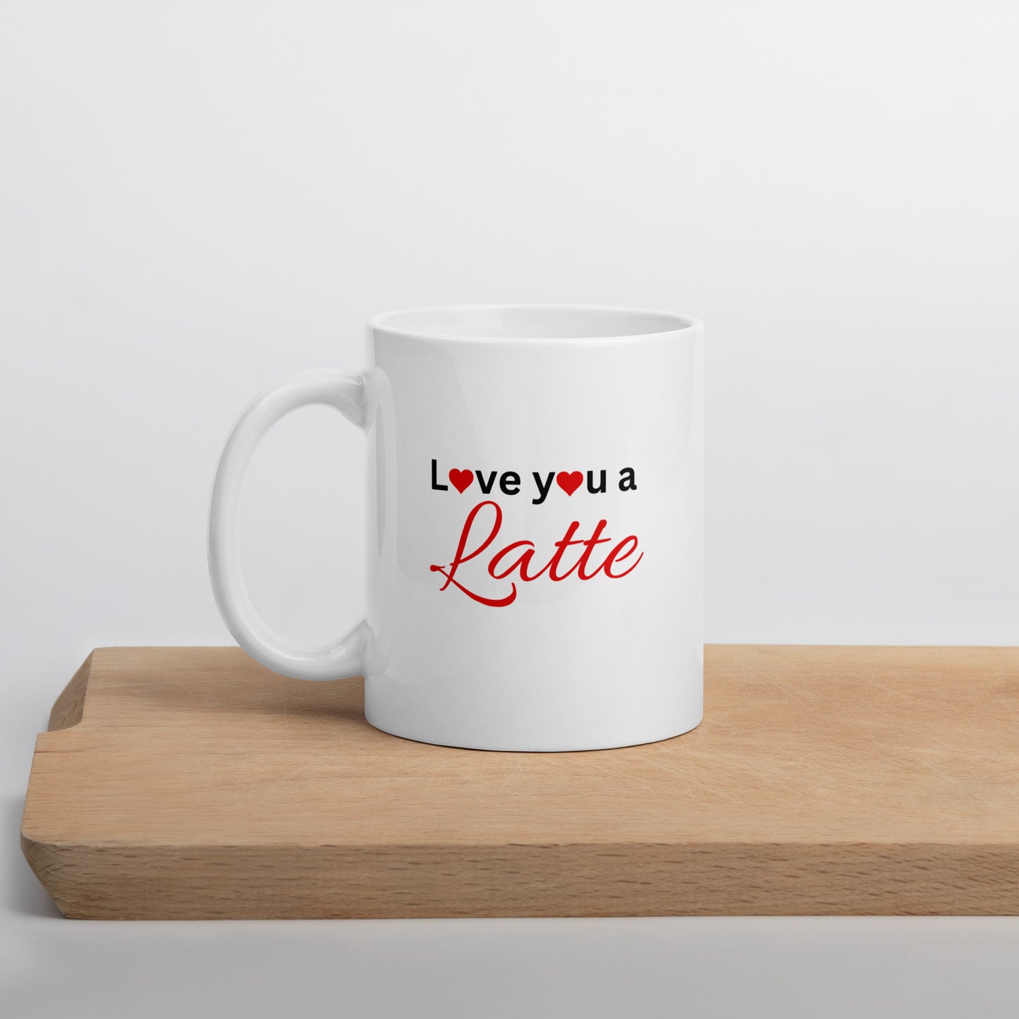 A white ceramic mug with the text 'I love you a latte' printed in red and a heart symbol, placed on a wooden surface.
