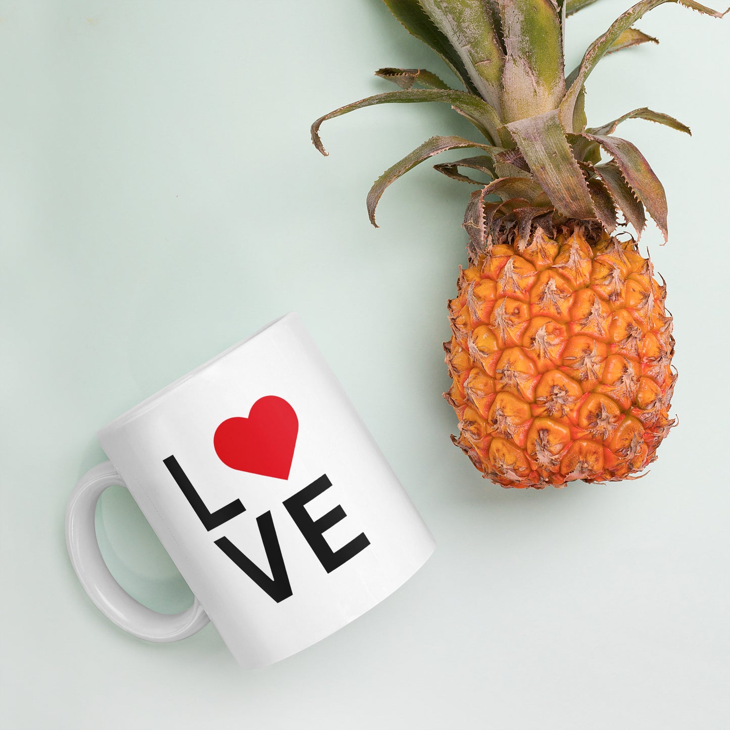 "White ceramic coffee mug with black text saying Love with red heart symbol"