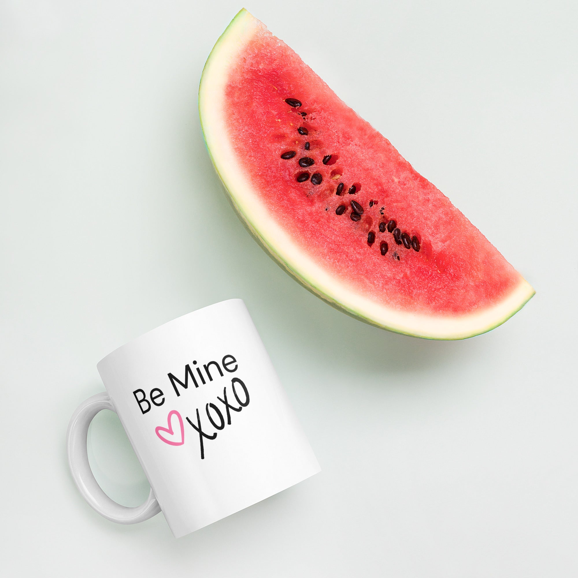 White ceramic coffee mug with black text saying Be Mine xoxo