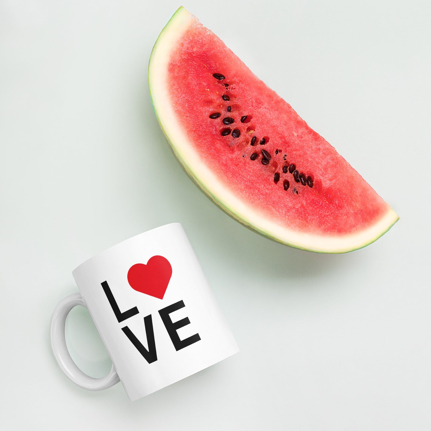 "White ceramic coffee mug with black text saying Love with red heart symbol"