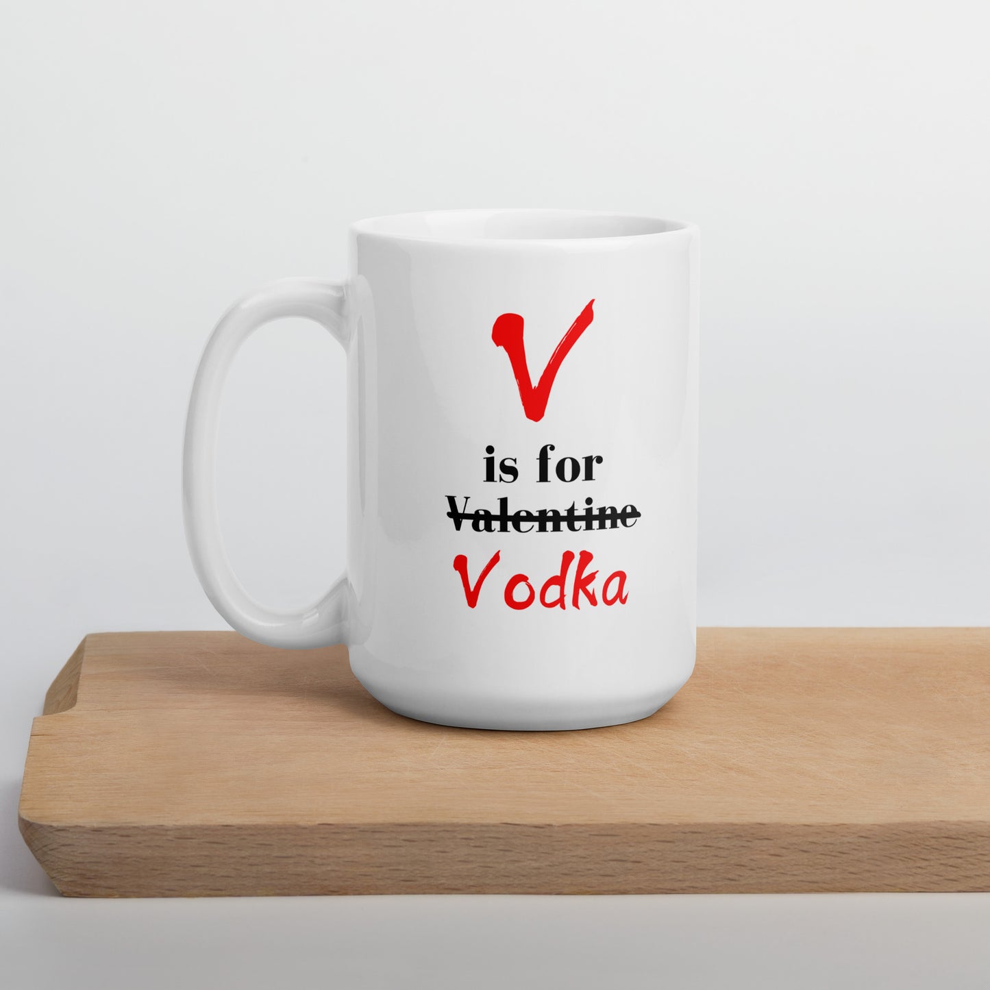 A white ceramic mug with 'V Is For Valentine Vodka' text and a red heart symbol, placed on a wooden board.