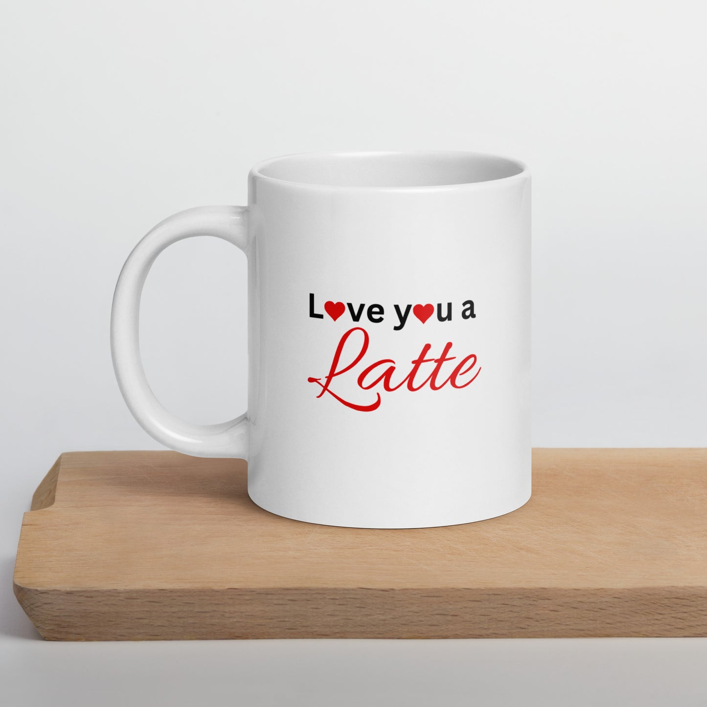 A white ceramic mug with the text 'I love you a latte' printed in red and a heart symbol, placed on a wooden surface.