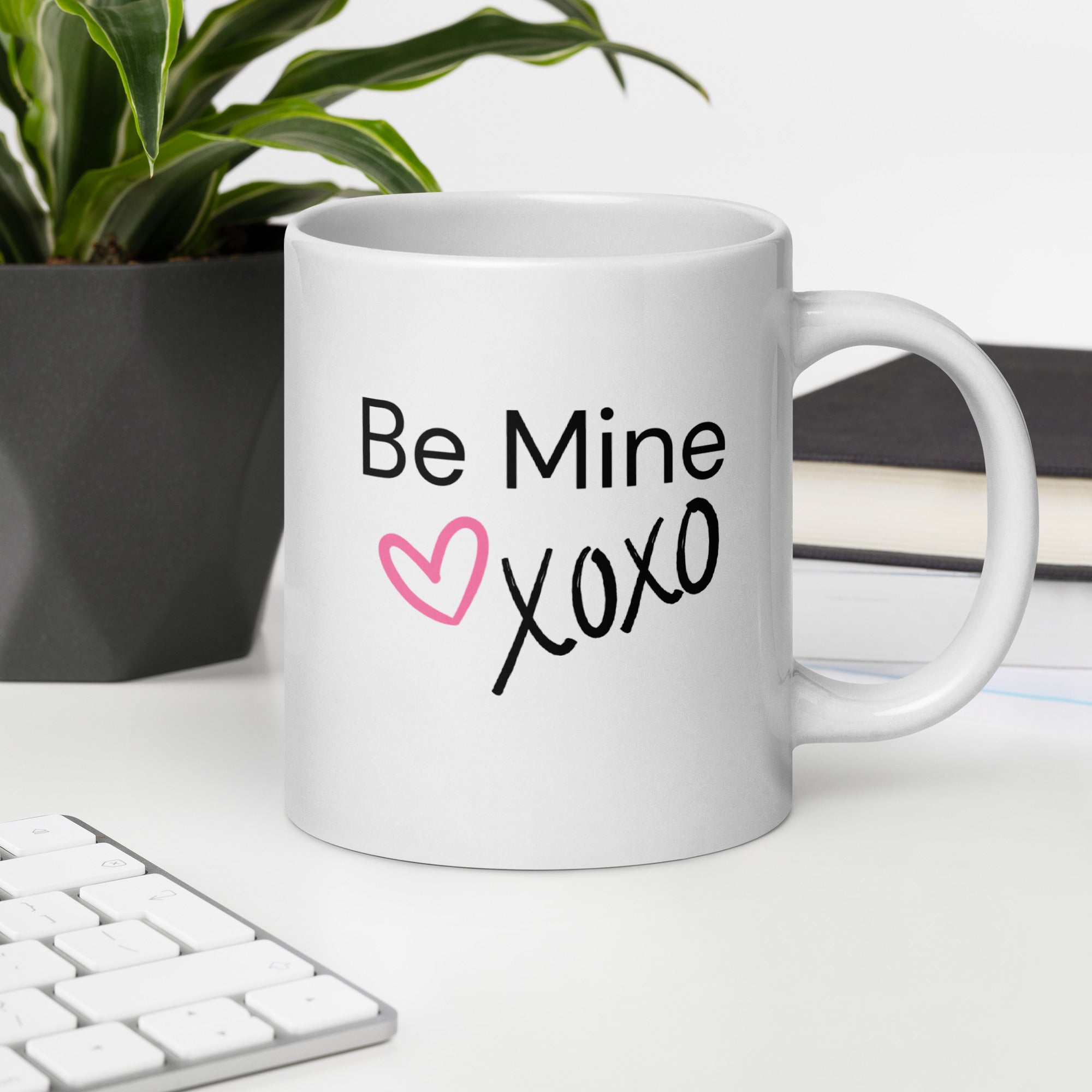 White ceramic coffee mug with black text saying Be Mine xoxo