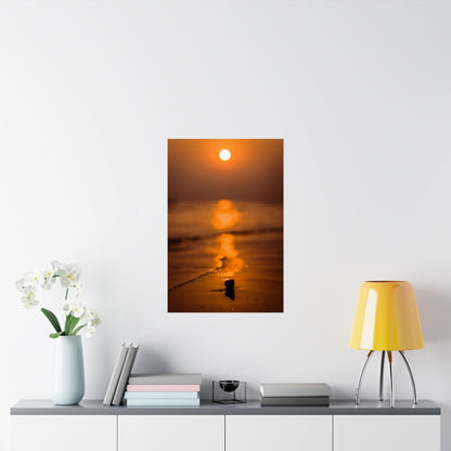 Sunset over water with a small boat on a white wall above a shelf with decor items.
