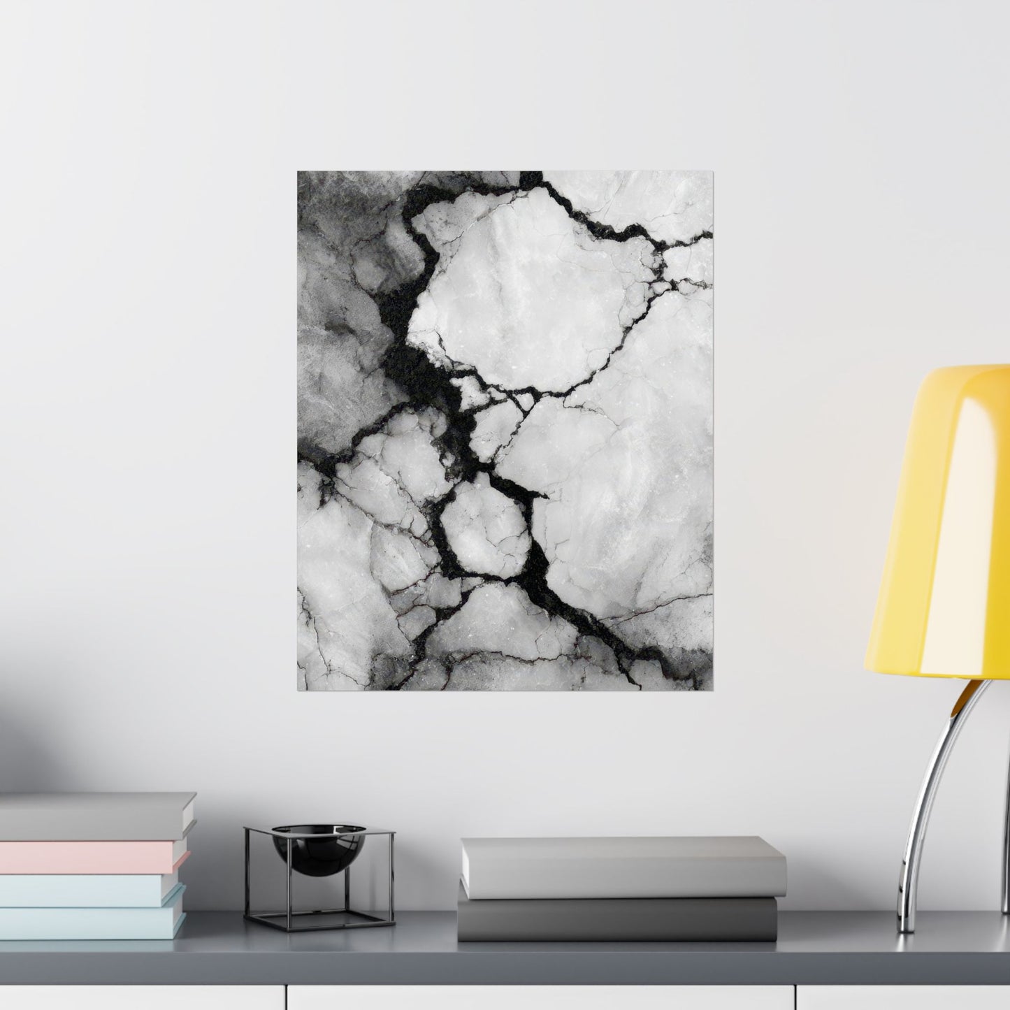 Marble-patterned wall art on a white wall with books and a lamp in the foreground.