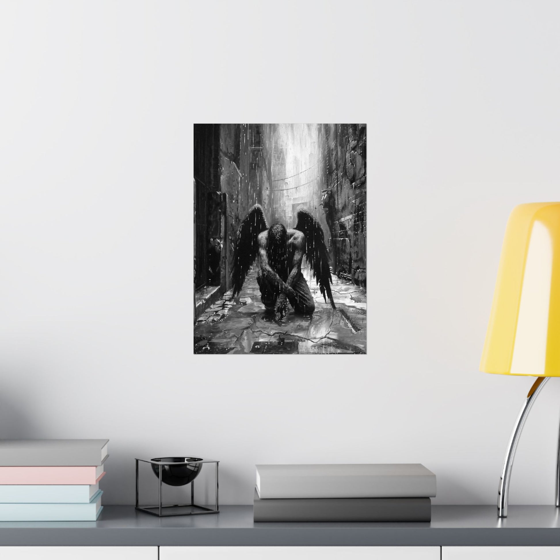 Framed artwork of an angel in a dark, industrial setting on a wall above a shelf with books and a lamp.