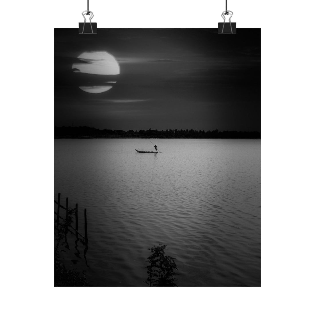 Black and white photo of a person in a boat on a lake at night with a large moon.
