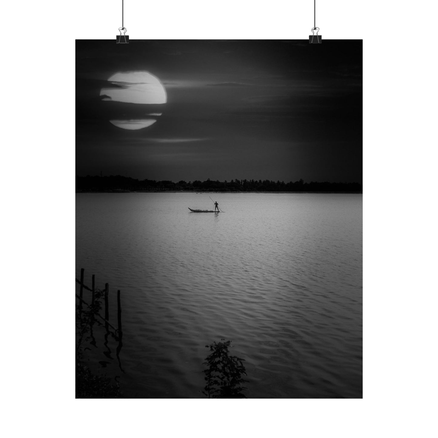 Black and white photo of a person in a boat on a lake at night with a large moon.