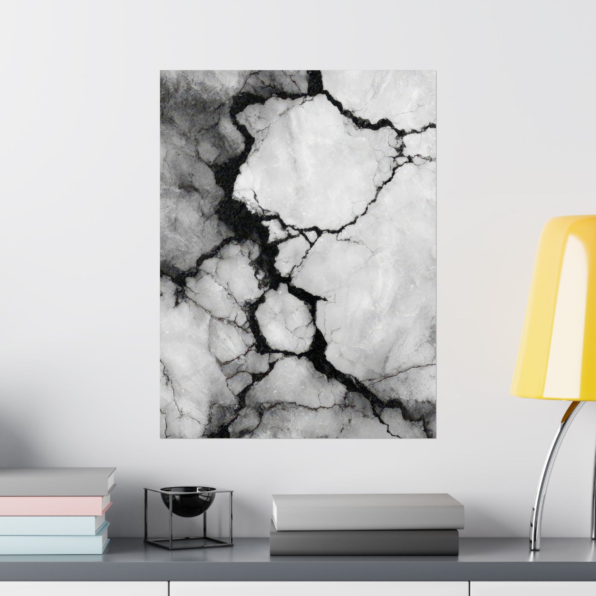 Marble-patterned wall art on a white wall with a yellow lamp and books in the foreground.