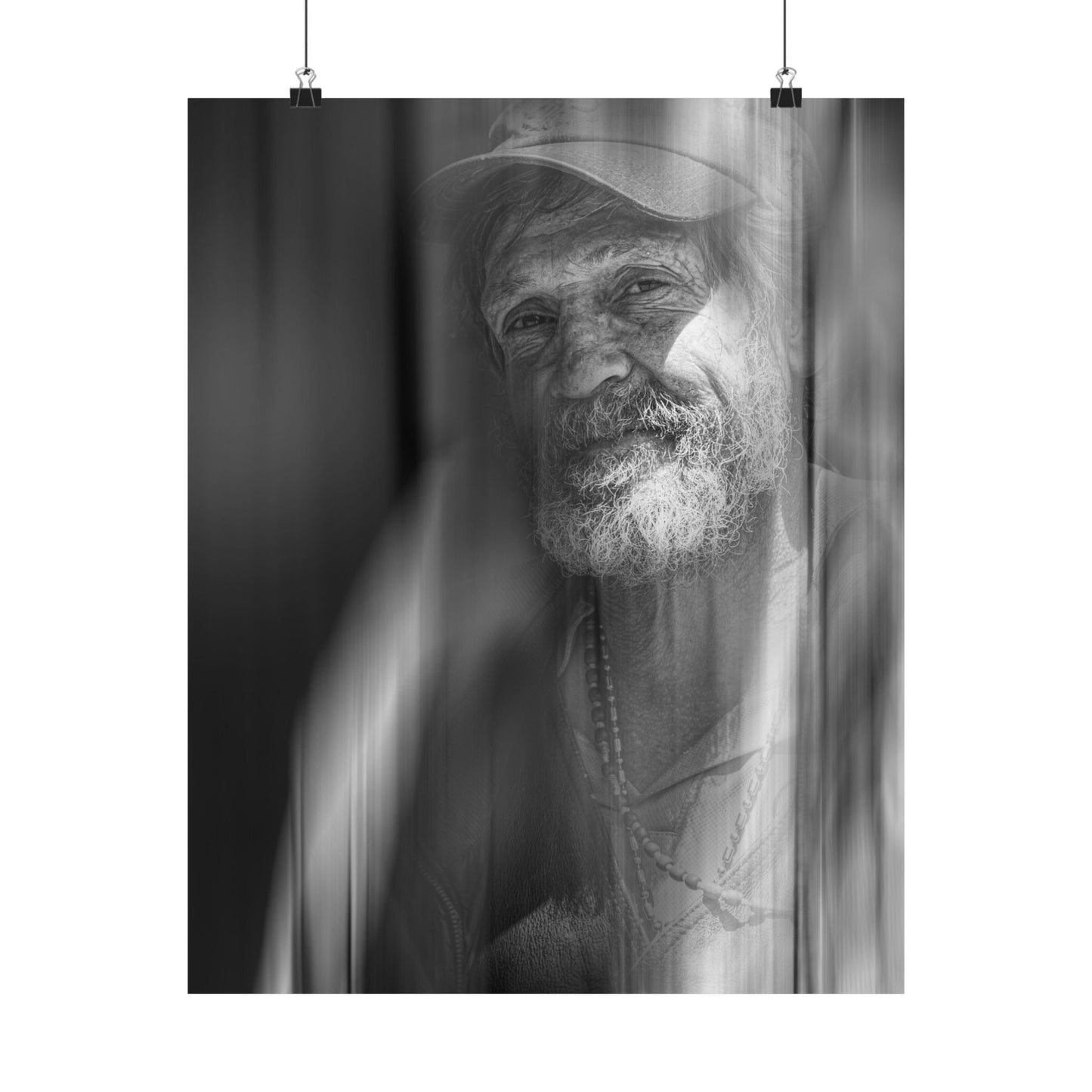 Black and white portrait of a man with a beard and hat, hanging on a white wall.