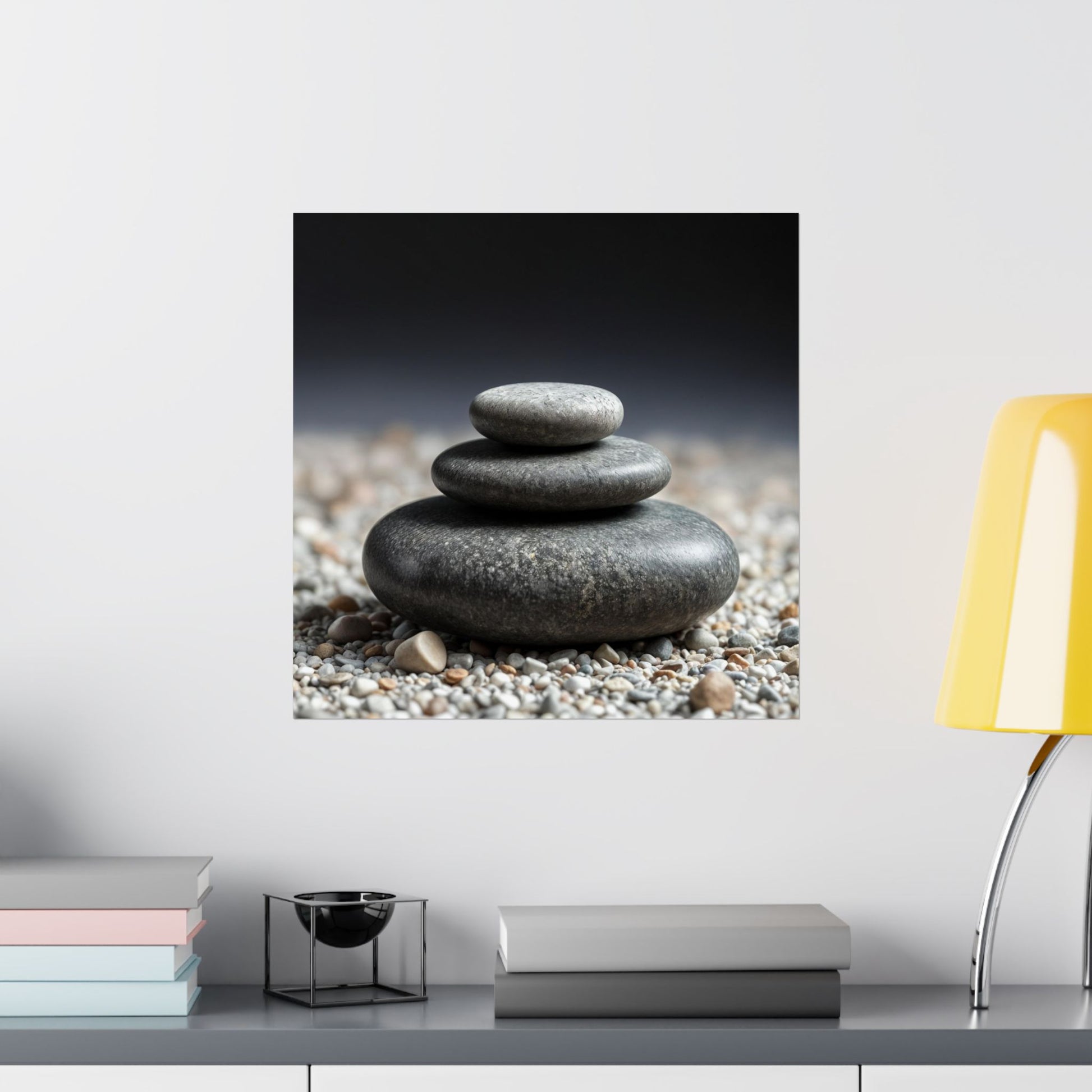 Stack of stones on pebbles with a yellow lamp and books in the background