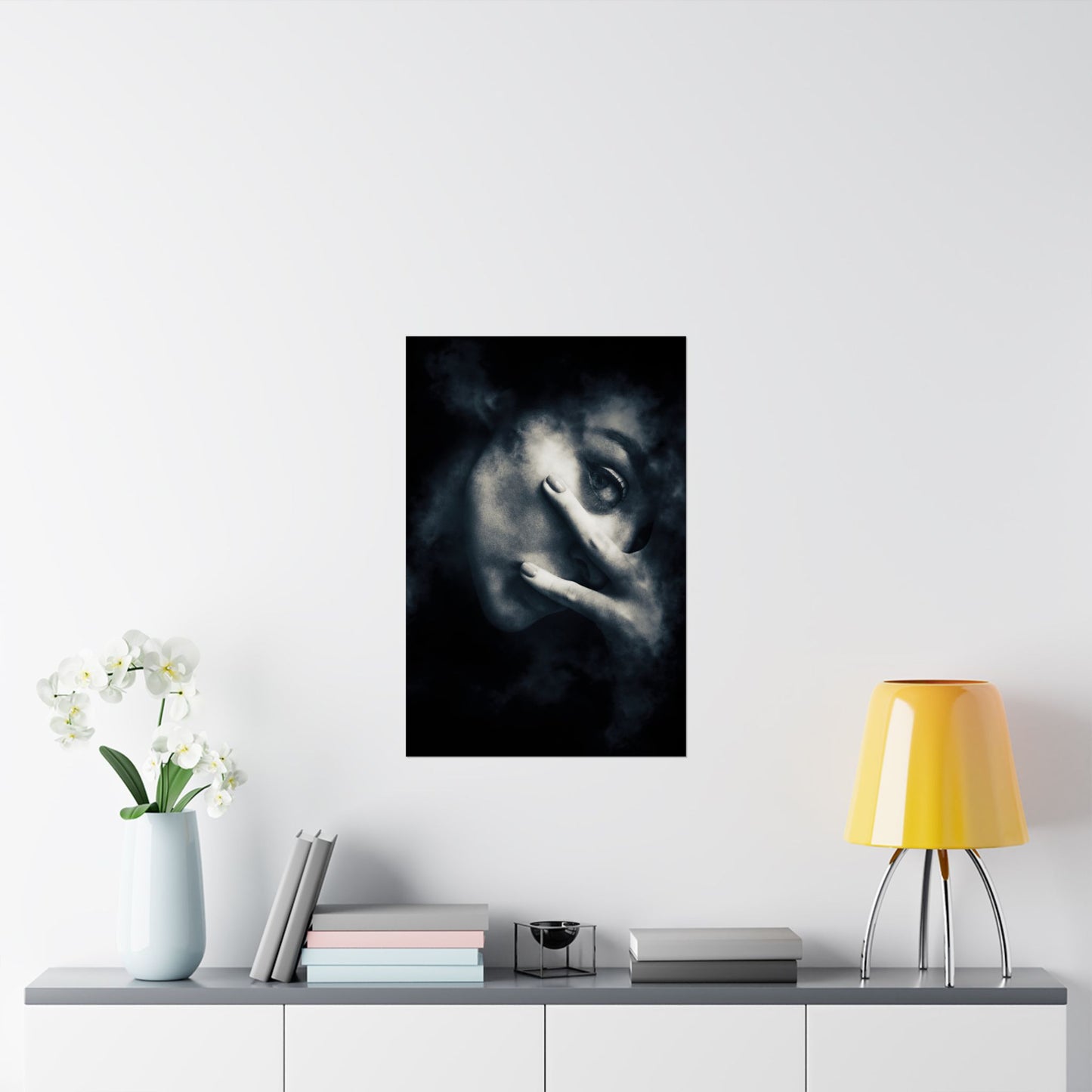 Framed artwork of a face on a wall above a shelf with decor items.