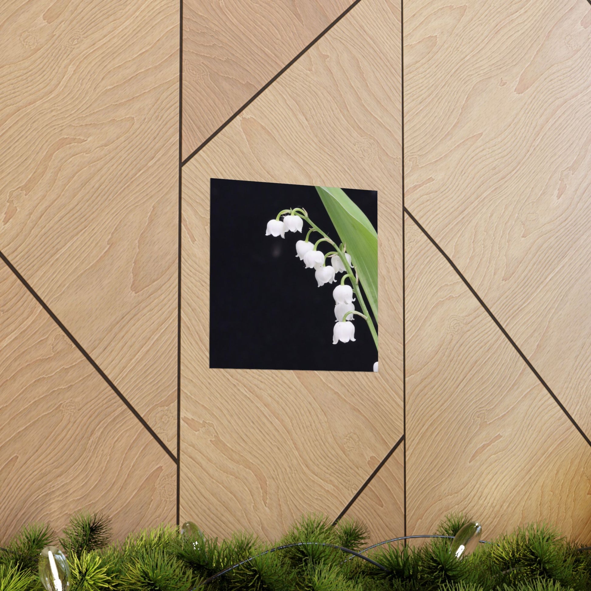 Framed picture of white flowers on a wooden wall with greenery at the bottom.