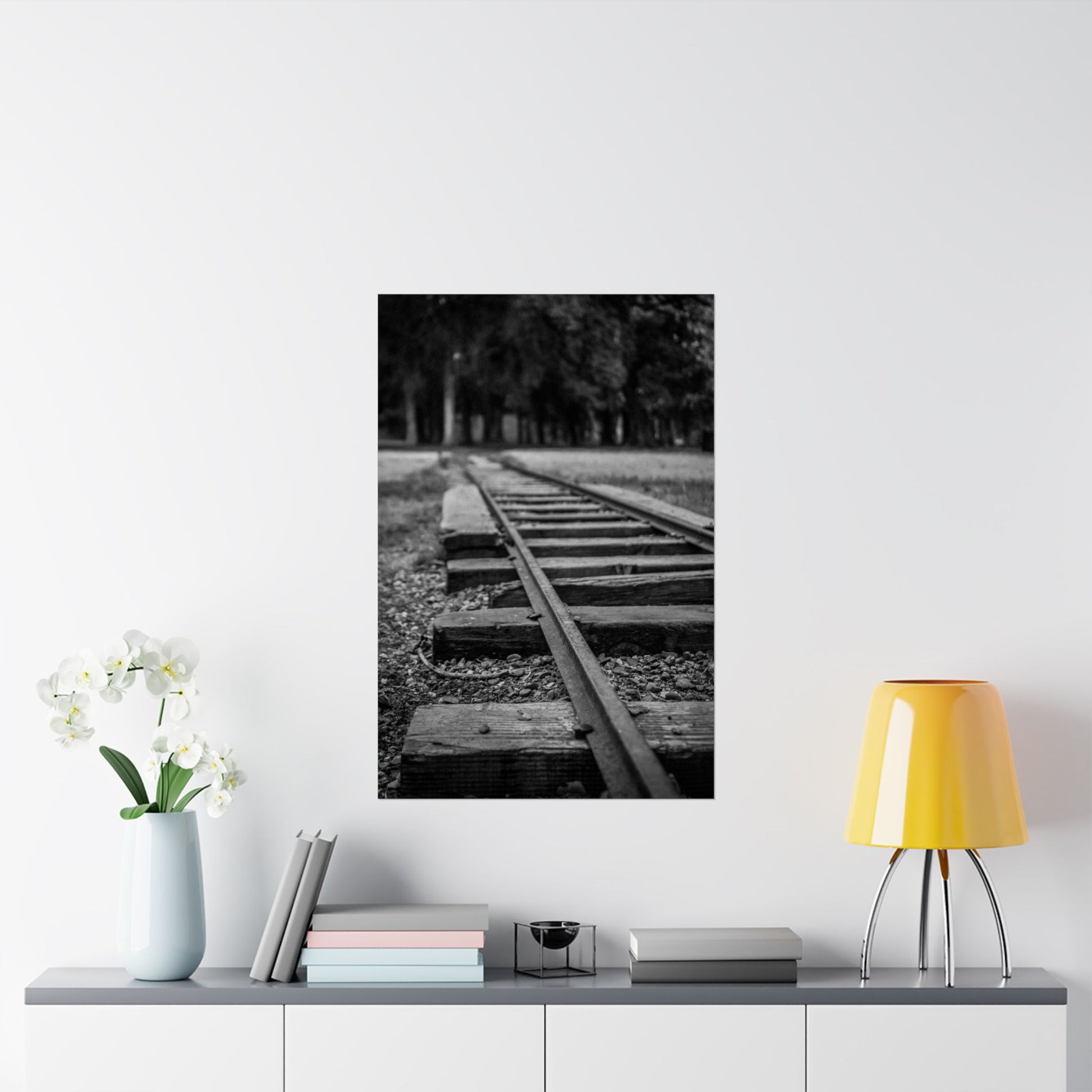 Framed black and white photo of a railway track on a wall above a shelf with decor items.