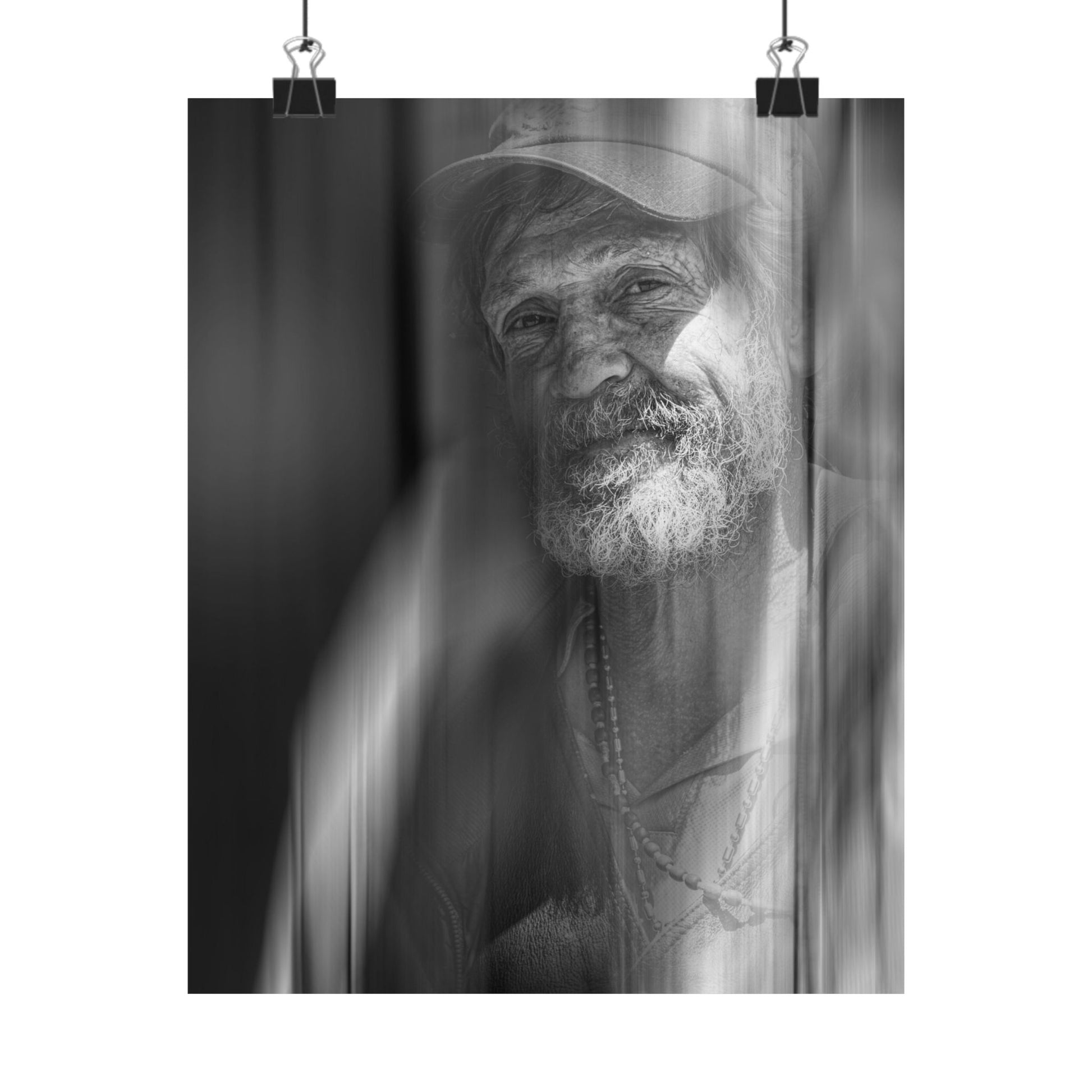 Black and white portrait of a man with a beard and hat, framed by curtains.