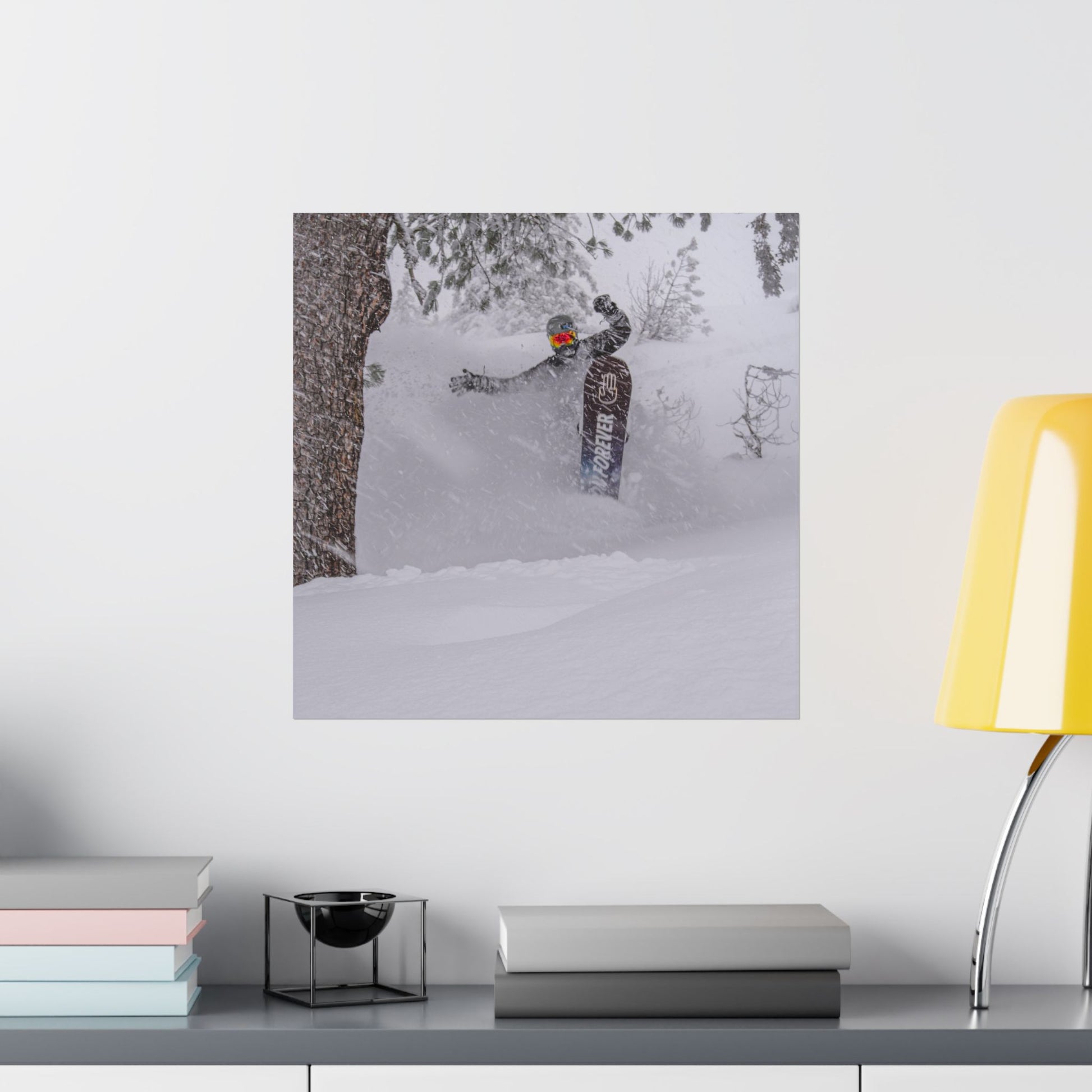 Poster of a person snowboarding on a wall above a desk with books and a lamp.