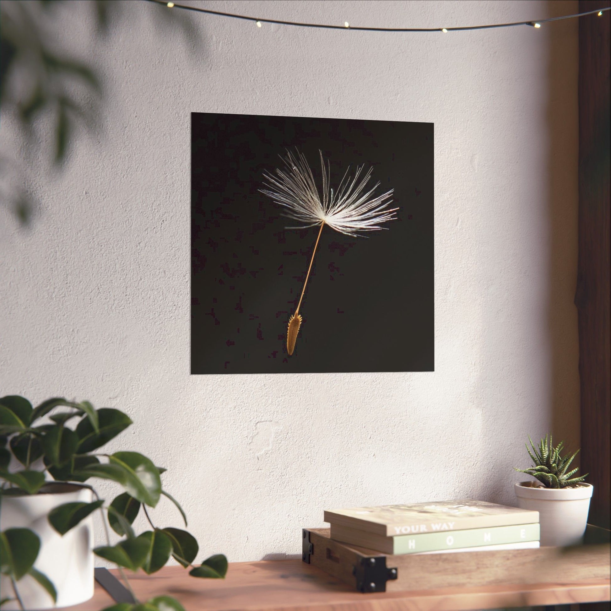 Dandelion seed head artwork on a wall with plants and books below