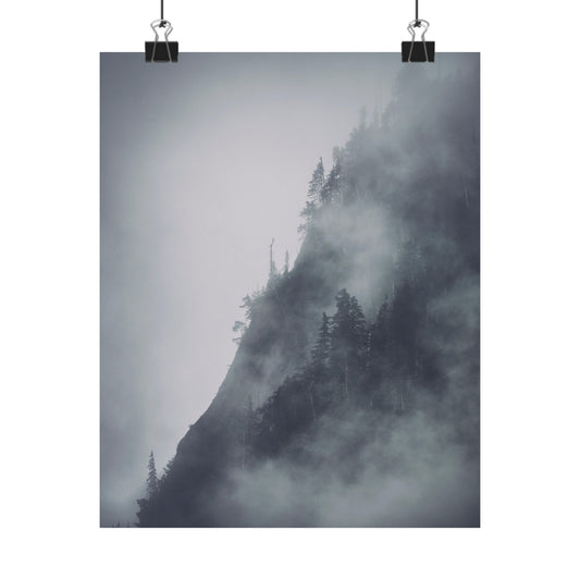 Mountain covered in mist with trees, framed by paper clips on a white background