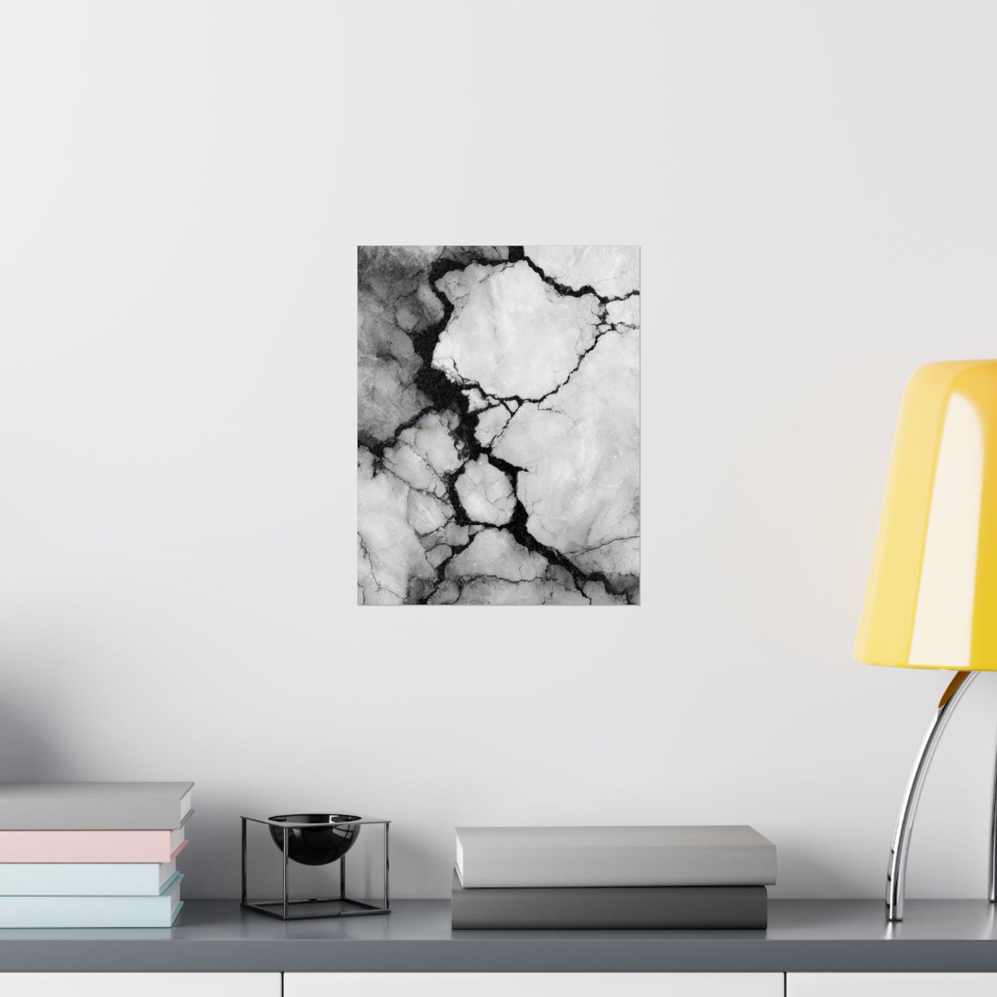 Abstract black and white marble art print on a wall above a shelf with books and decor items.