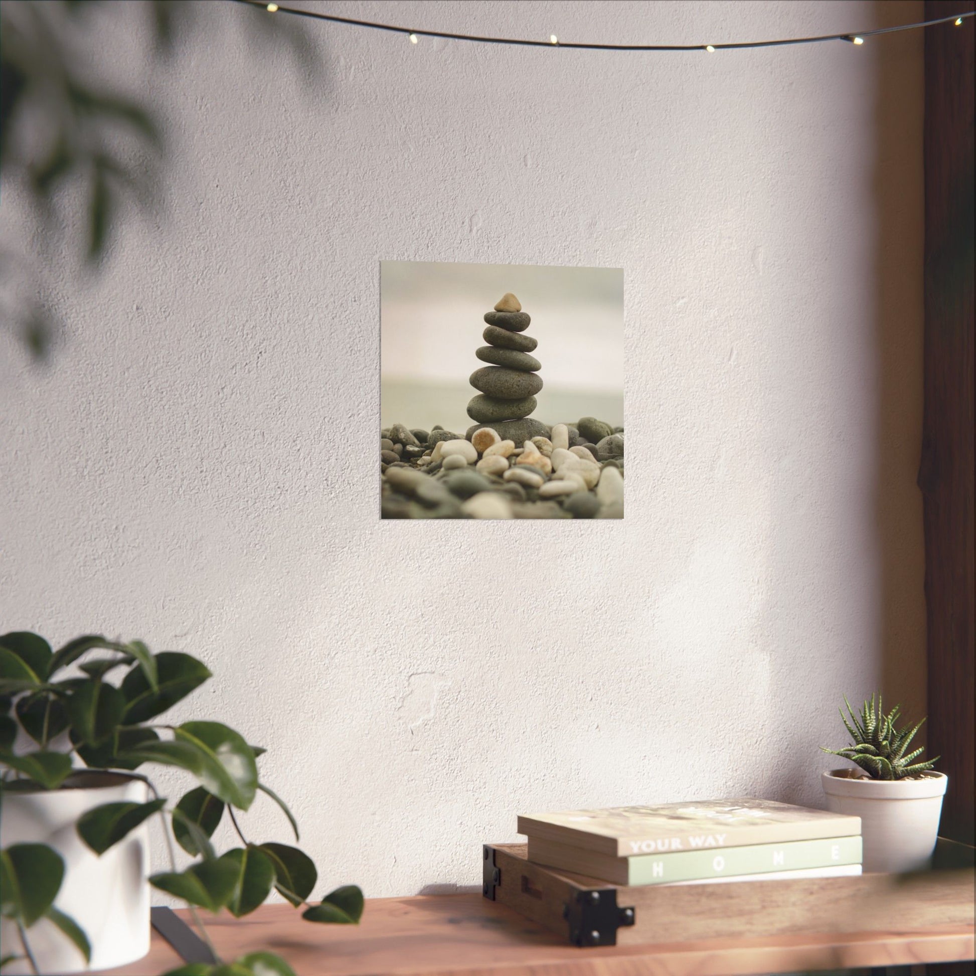 Stylized image of stacked stones on a wall with plants and books on a table below.
