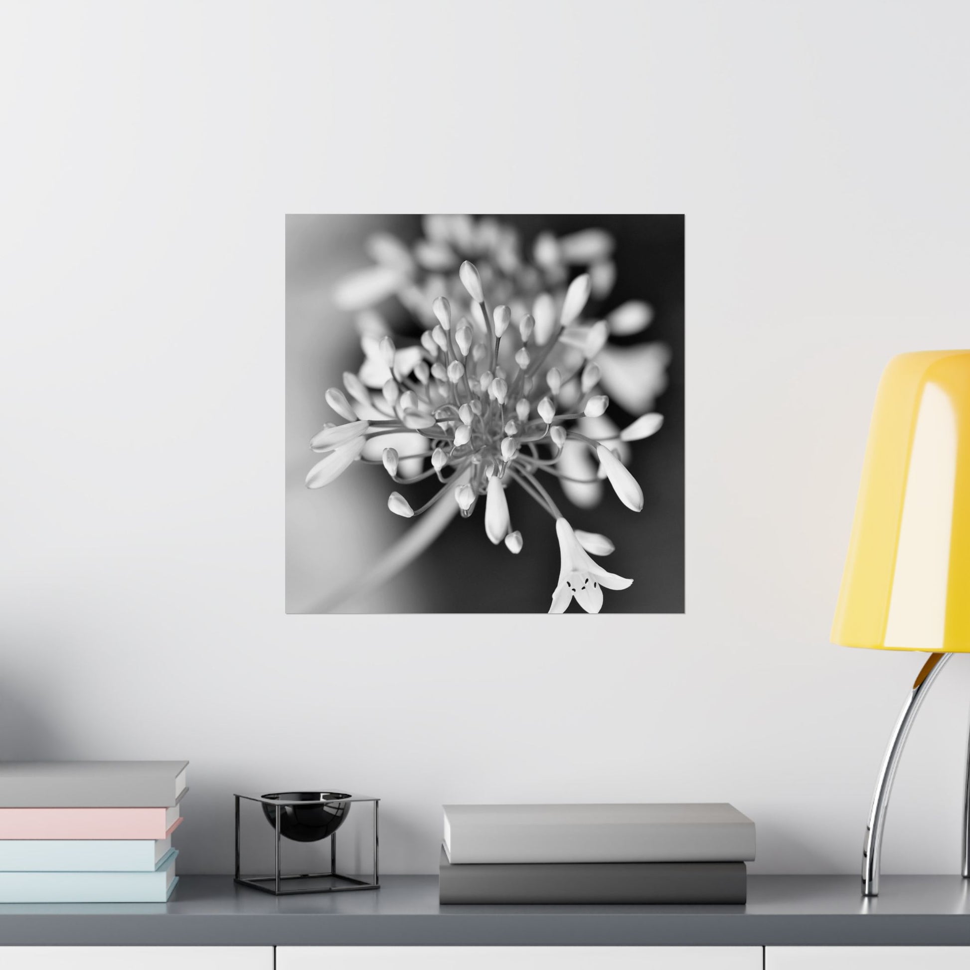 Floral artwork on a wall above a shelf with books and a lamp.