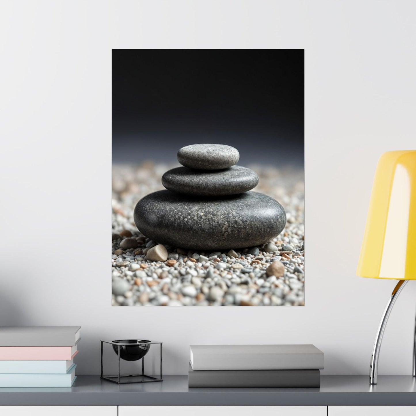 Stylized image of stacked stones on pebbles with a blurred background, displayed on a wall above a shelf.