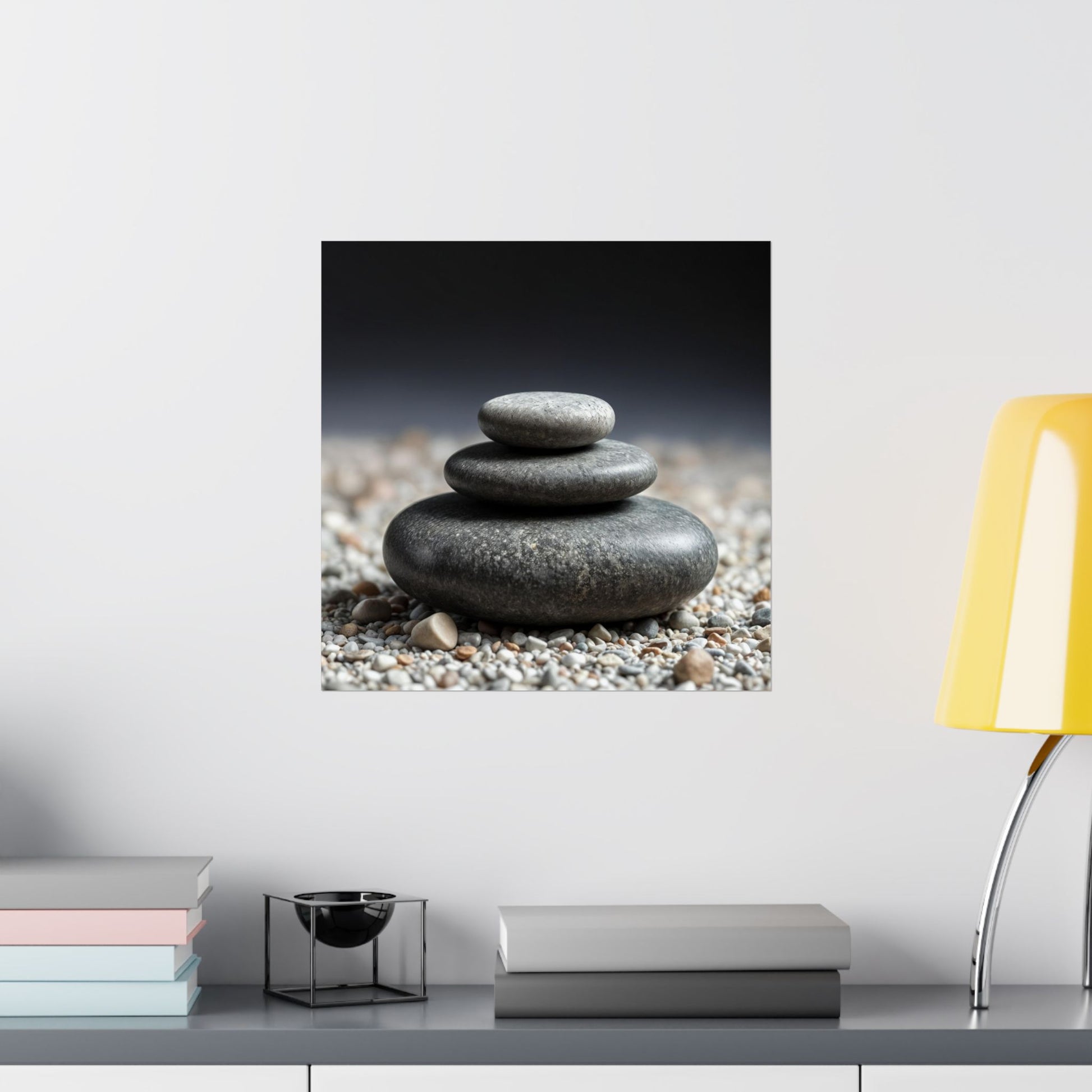 Canvas print of stacked stones on a wall above a desk with books and a lamp.