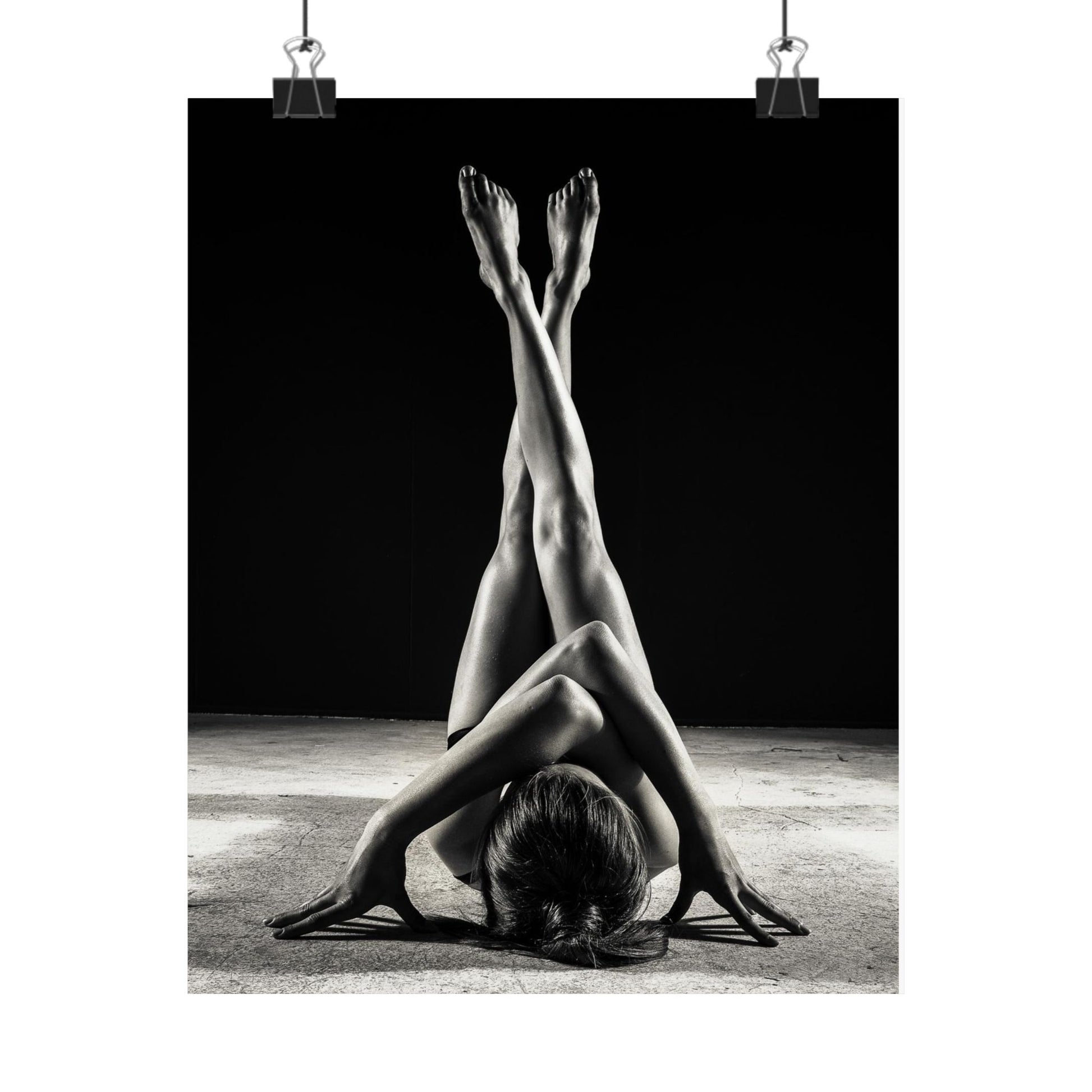 Black and white photo of a person stretching with legs in the air against a dark background