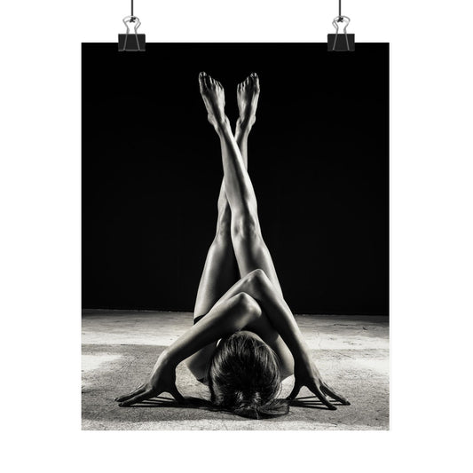 Black and white photo of a person stretching with legs in the air against a dark background