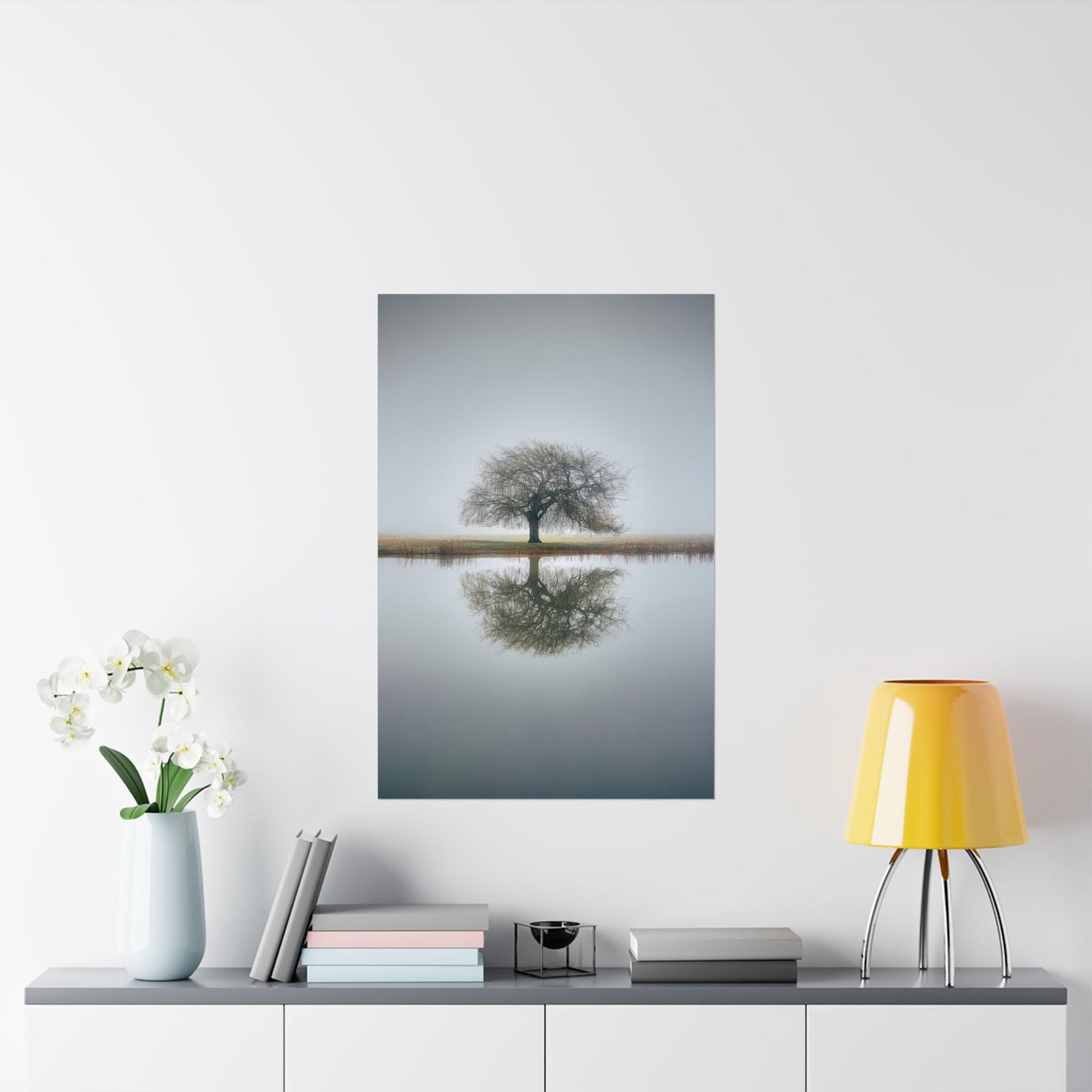 Framed artwork of a tree reflected in water on a wall above a shelf with decor items.