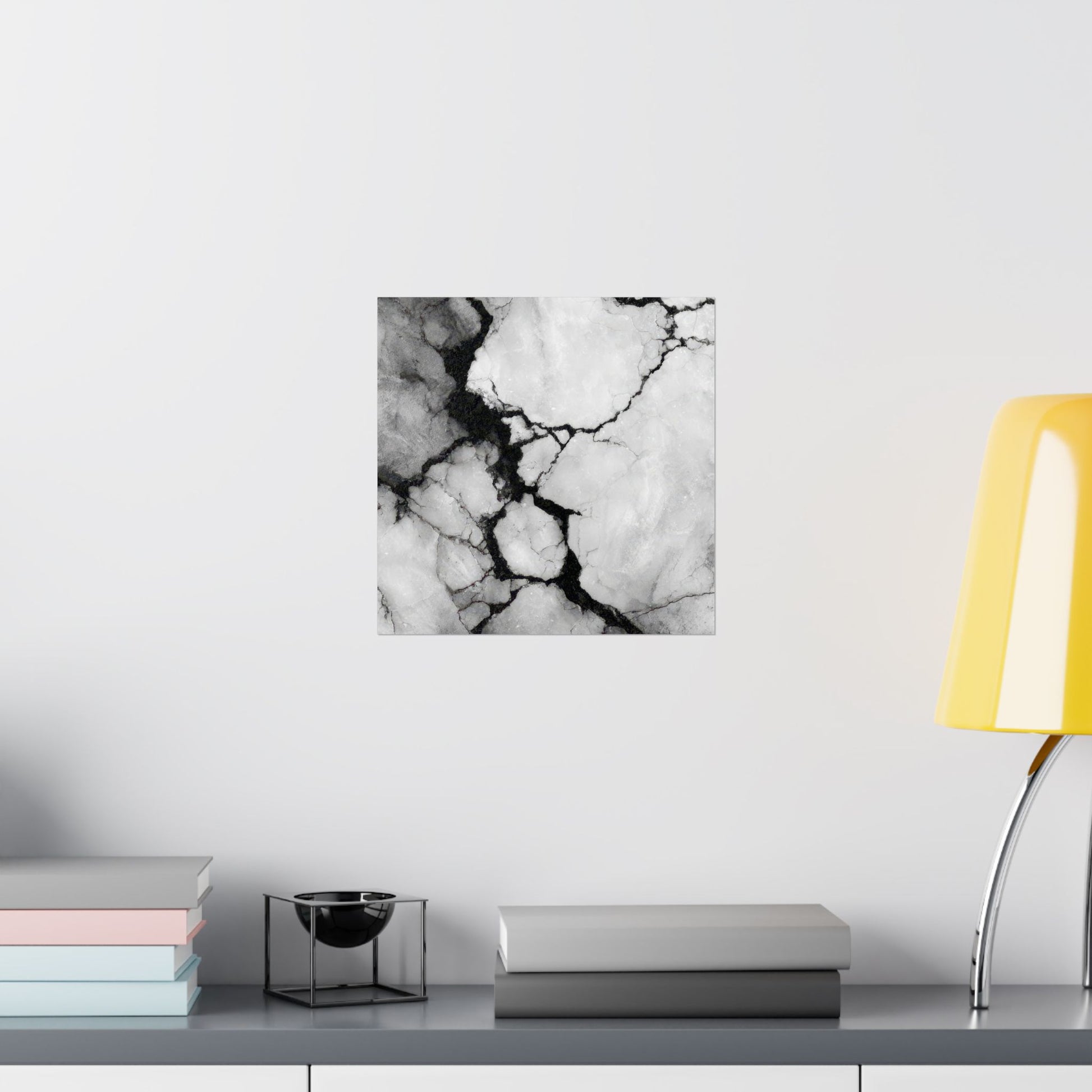 Black and white marble patterned wall art on a light gray wall with books and a lamp in the foreground.