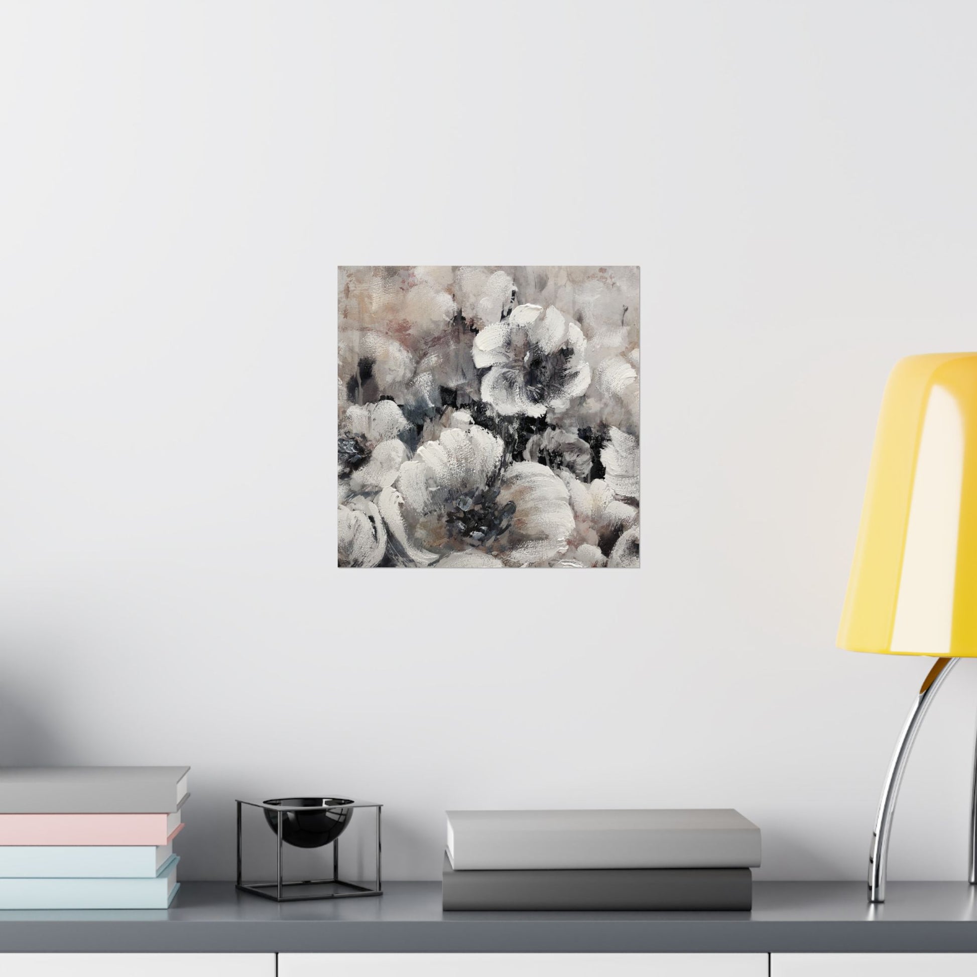 Abstract floral art piece on a wall above a shelf with books and a lamp.