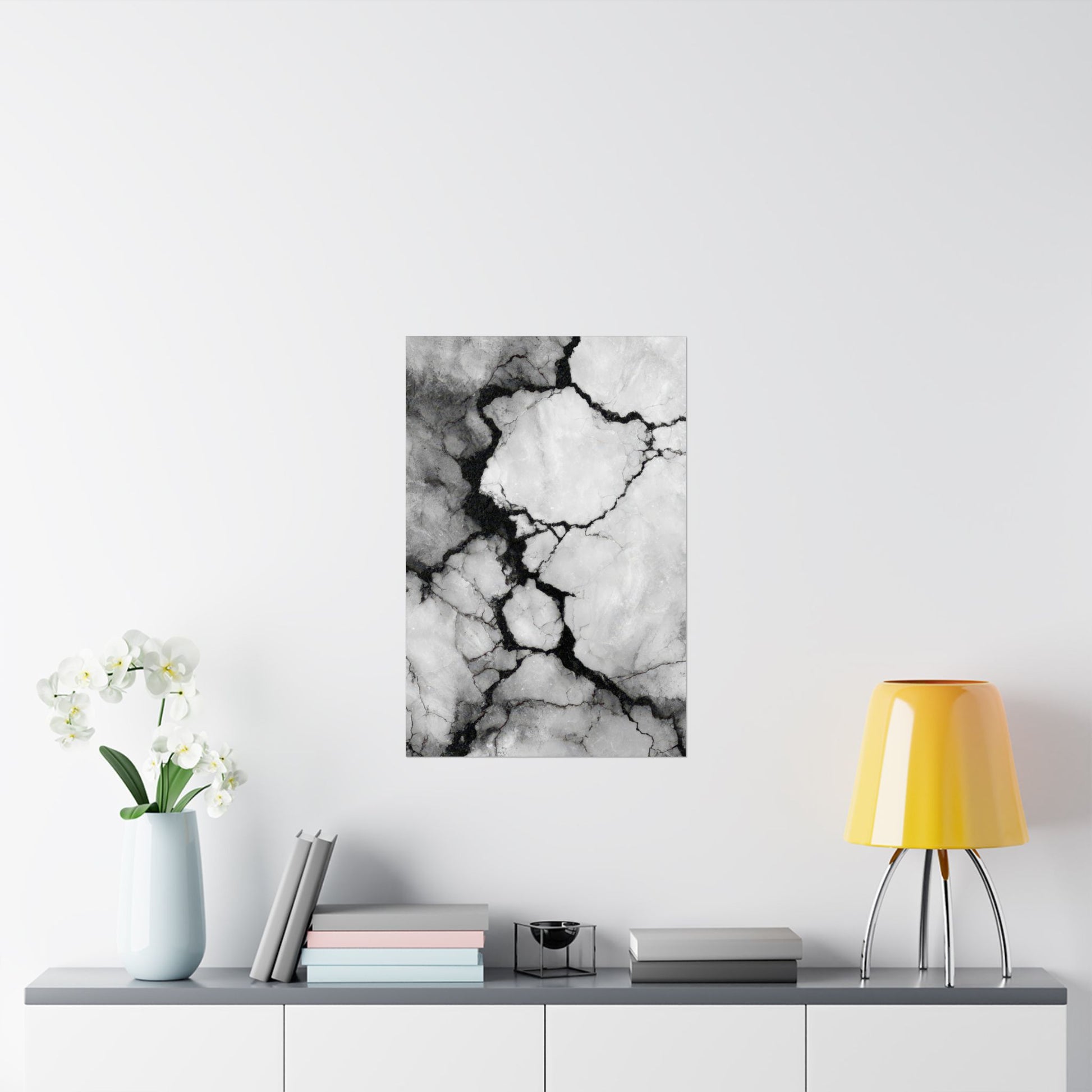 Abstract black and white marble art print on a wall above a shelf with decor items.