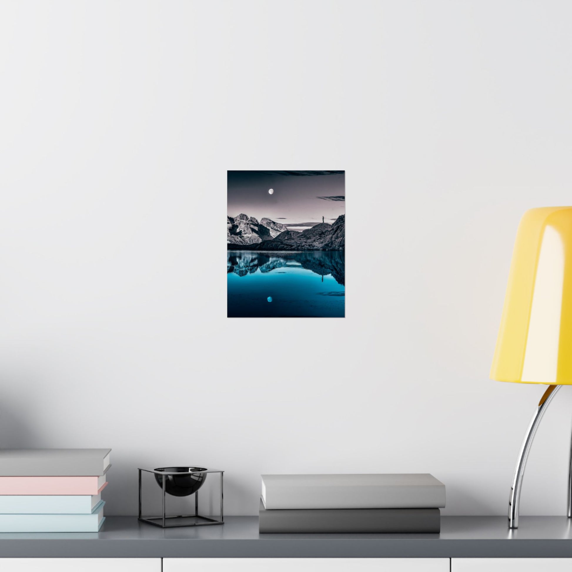 Framed artwork of a coastal scene with rocks and water on a white wall above a shelf.