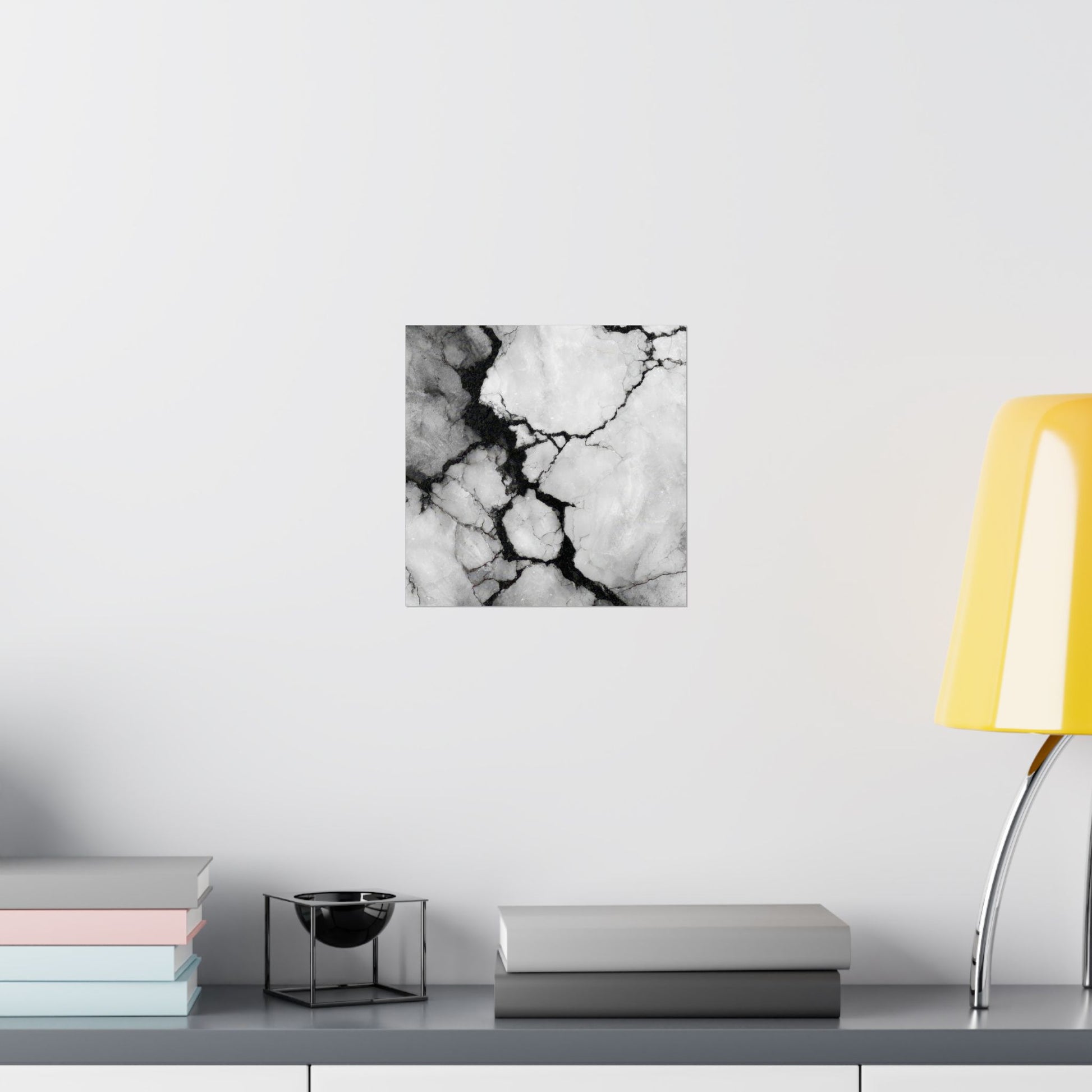 Abstract black and white marble print on a wall above a shelf with books and decor items.