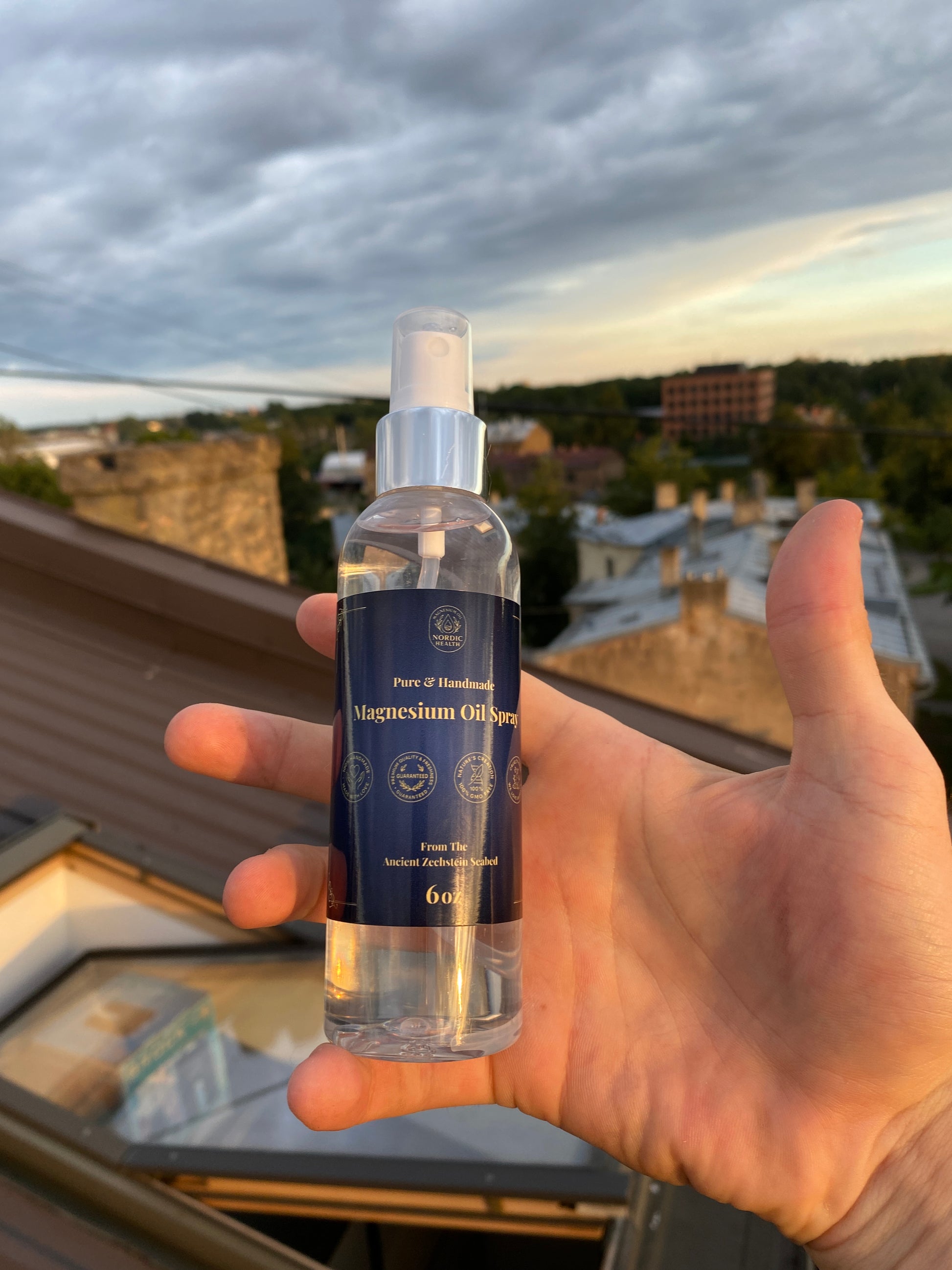 Hand holding a small blue bottle with a blurred outdoor background