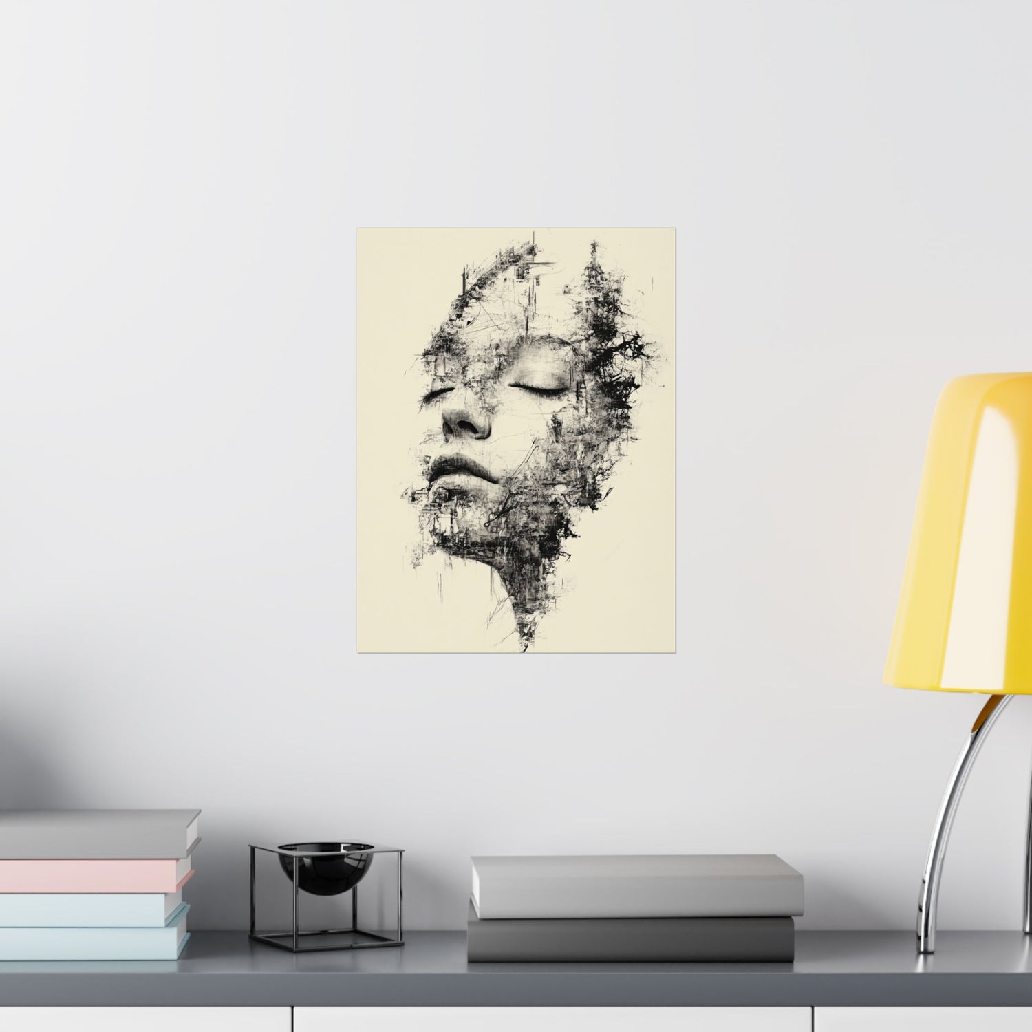 Abstract art print of a face on a wall above a shelf with books and a lamp.