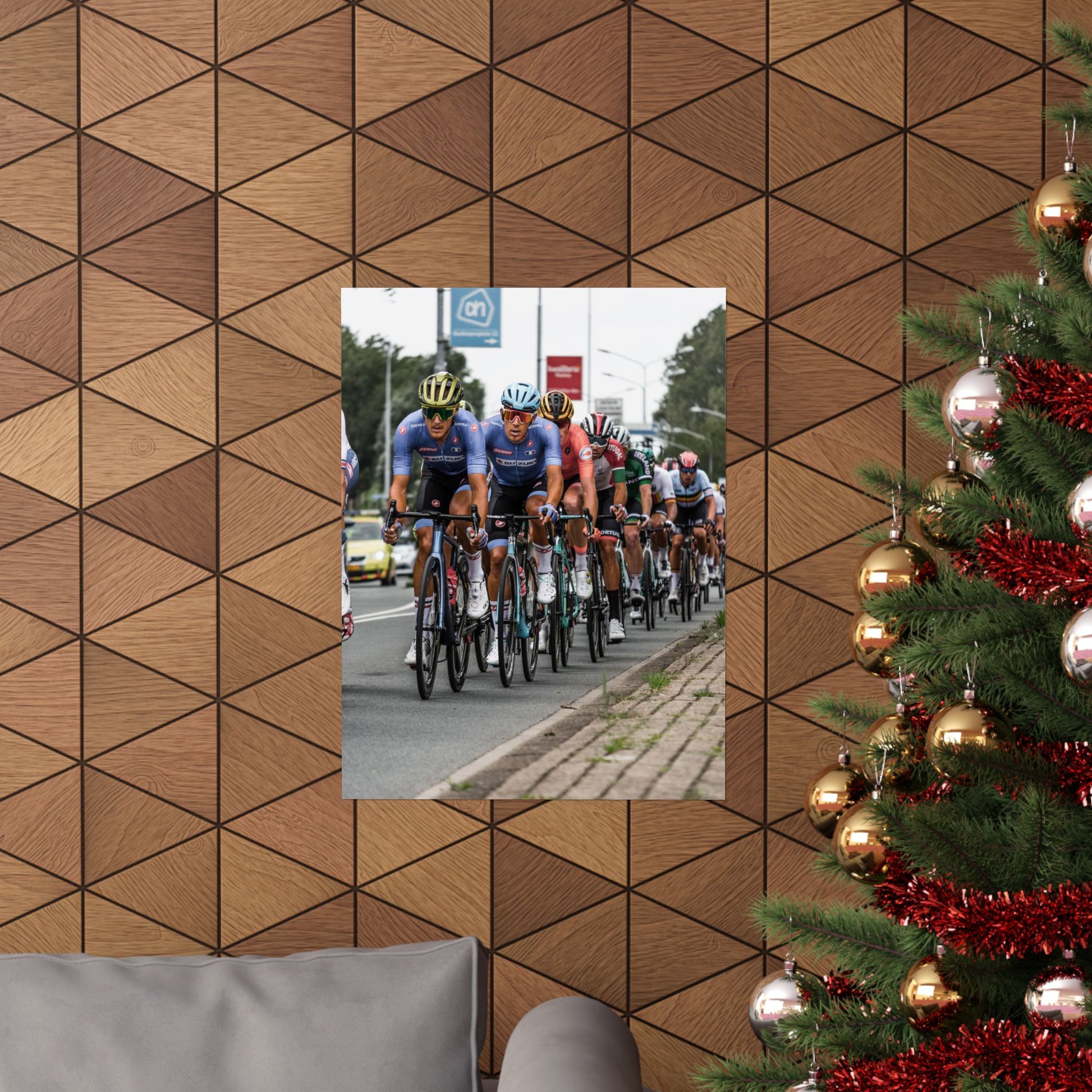 Cycling race on a road with a Christmas tree and geometric wall design in the foreground.